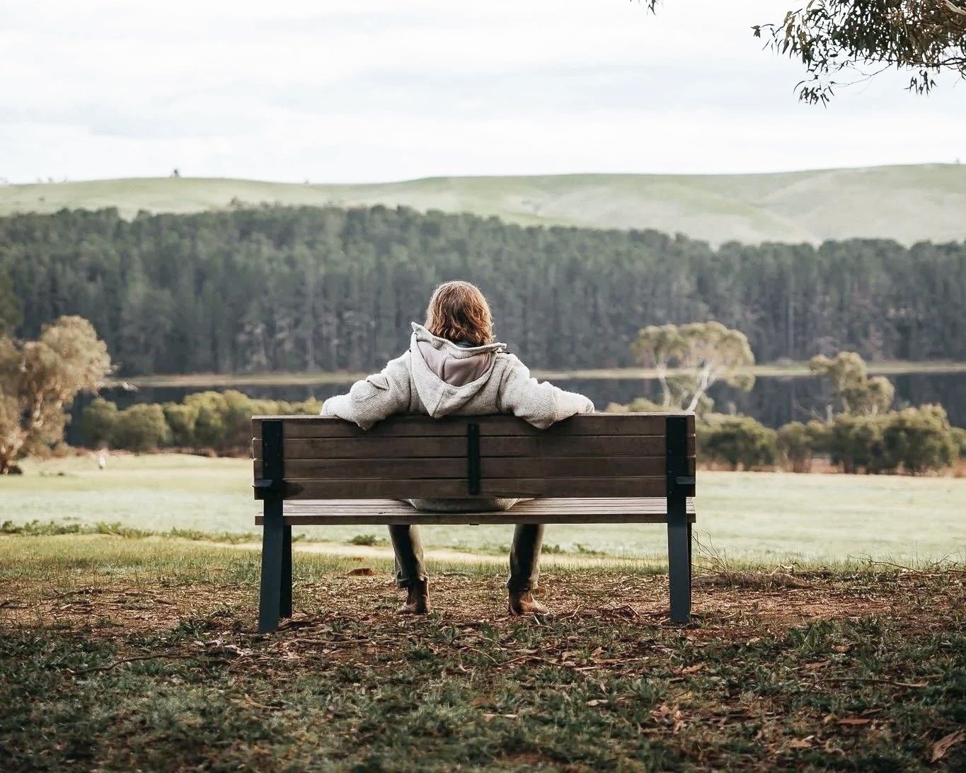 A person sitting alone on a bench in nature during a quiet moment of reflection.