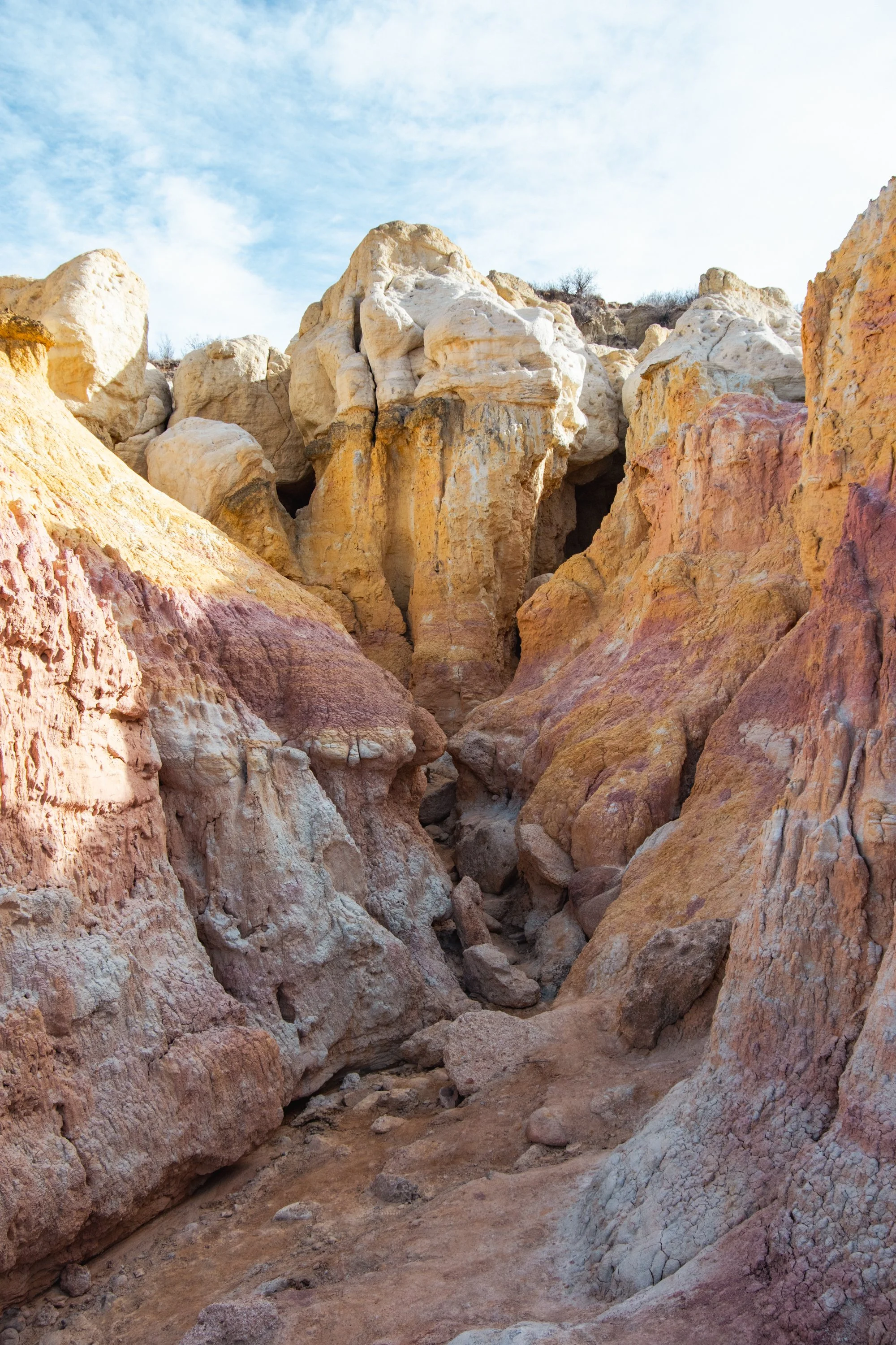 Colorful rock formations in a desert landscape with a partly cloudy sky.