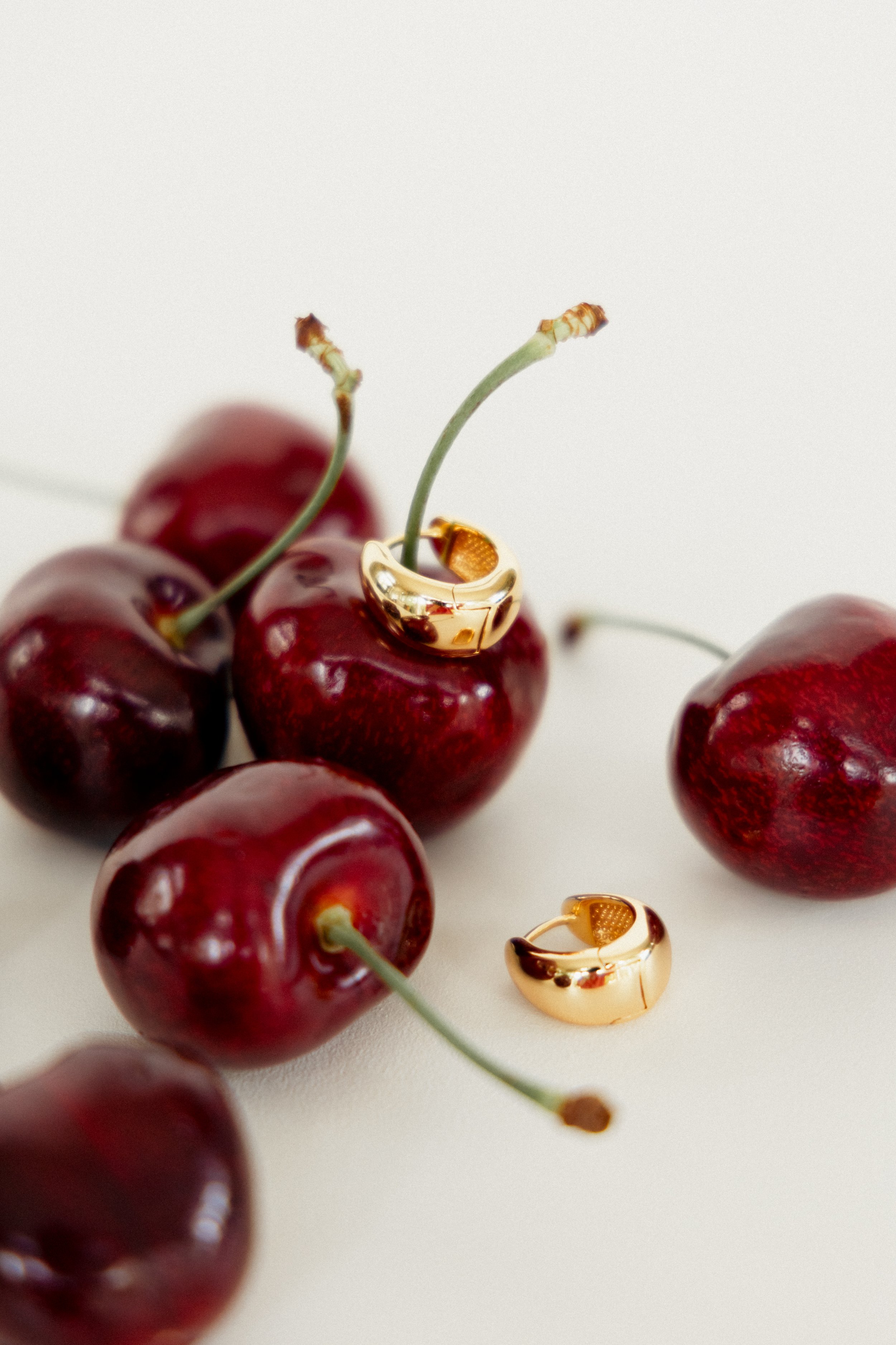 Creative jewellery product photography featuring gold rings styled with fresh cherries for La Dailie branding.