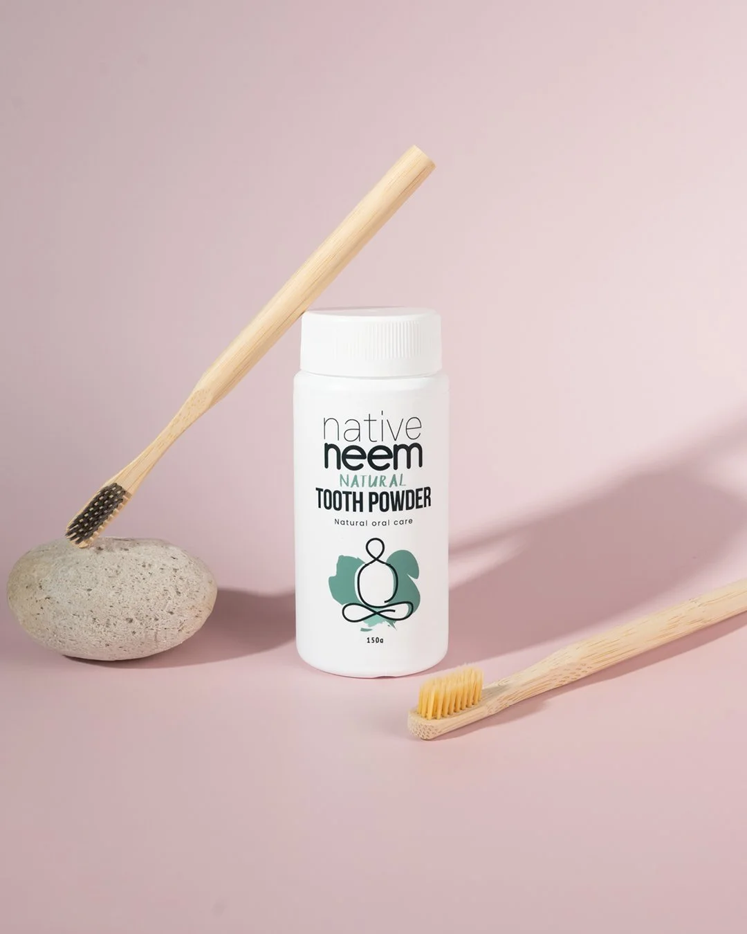 Product photography of Native Neem natural toothpaste featuring sustainable bamboo toothbrushes on a soft pink background.