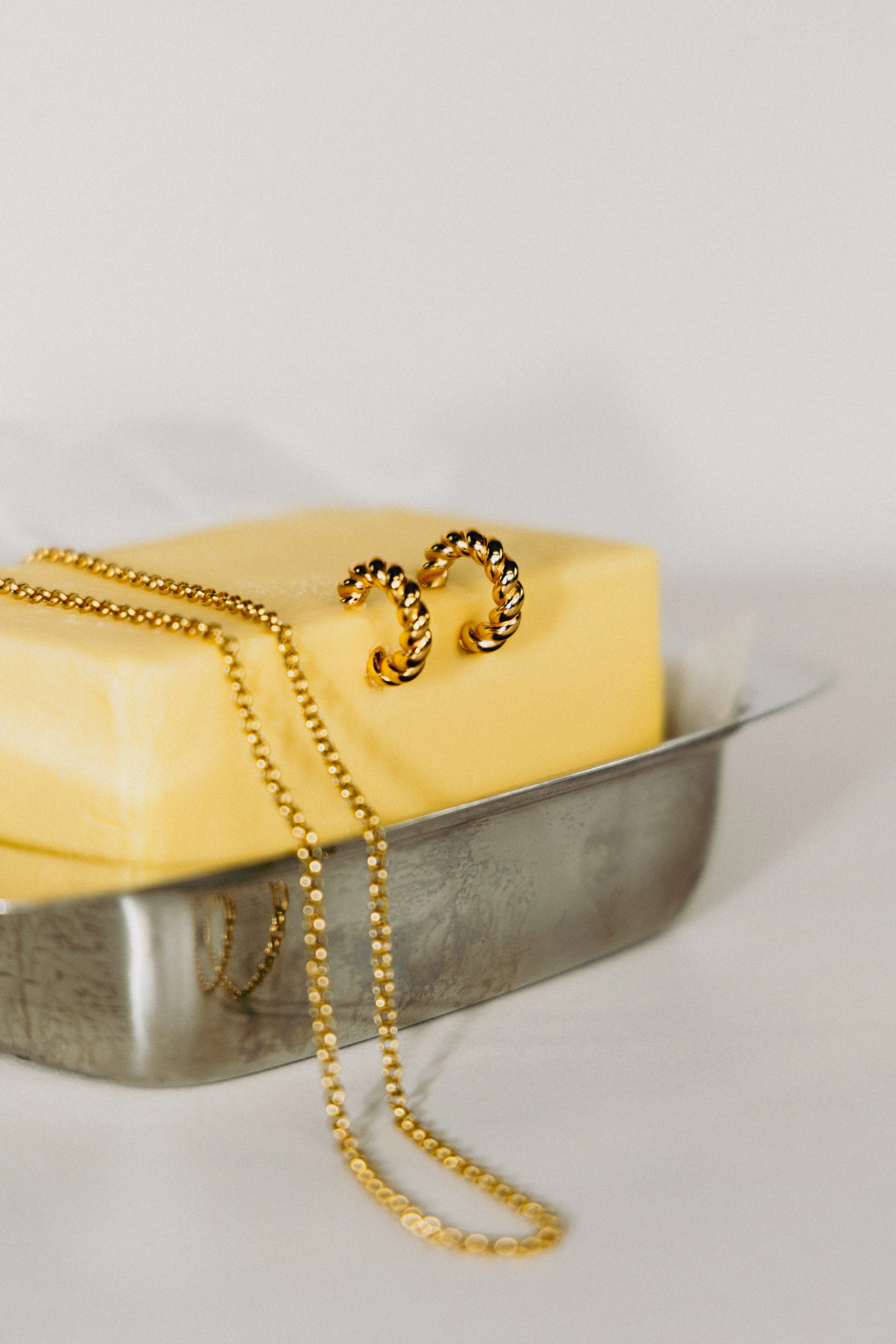 Creative lifestyle jewellery photography for La Dailie featuring a gold necklace styled with butter in a modern minimalist composition.