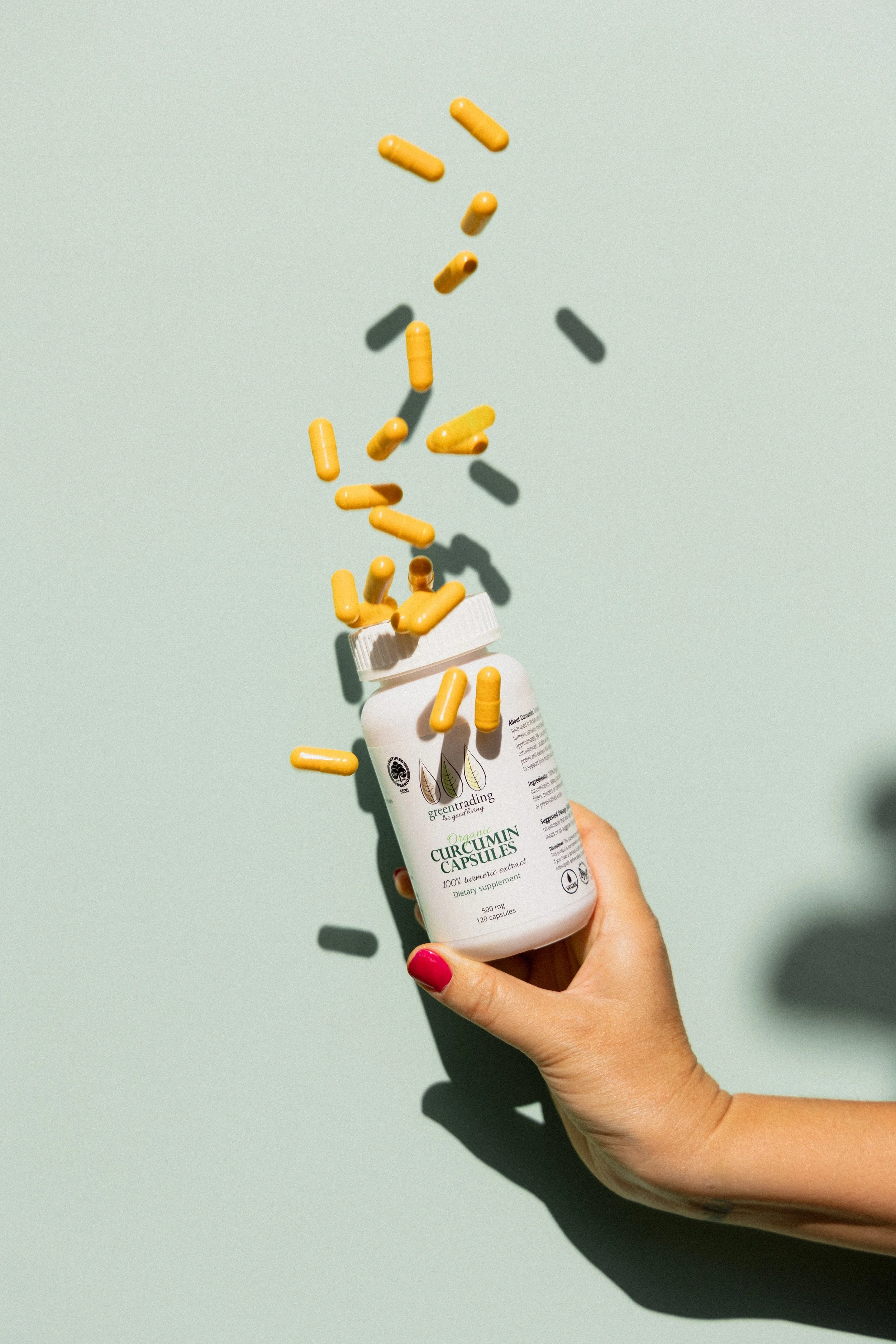 Creative product photography of a Green Trading supplement bottle with capsules for social media content creation.