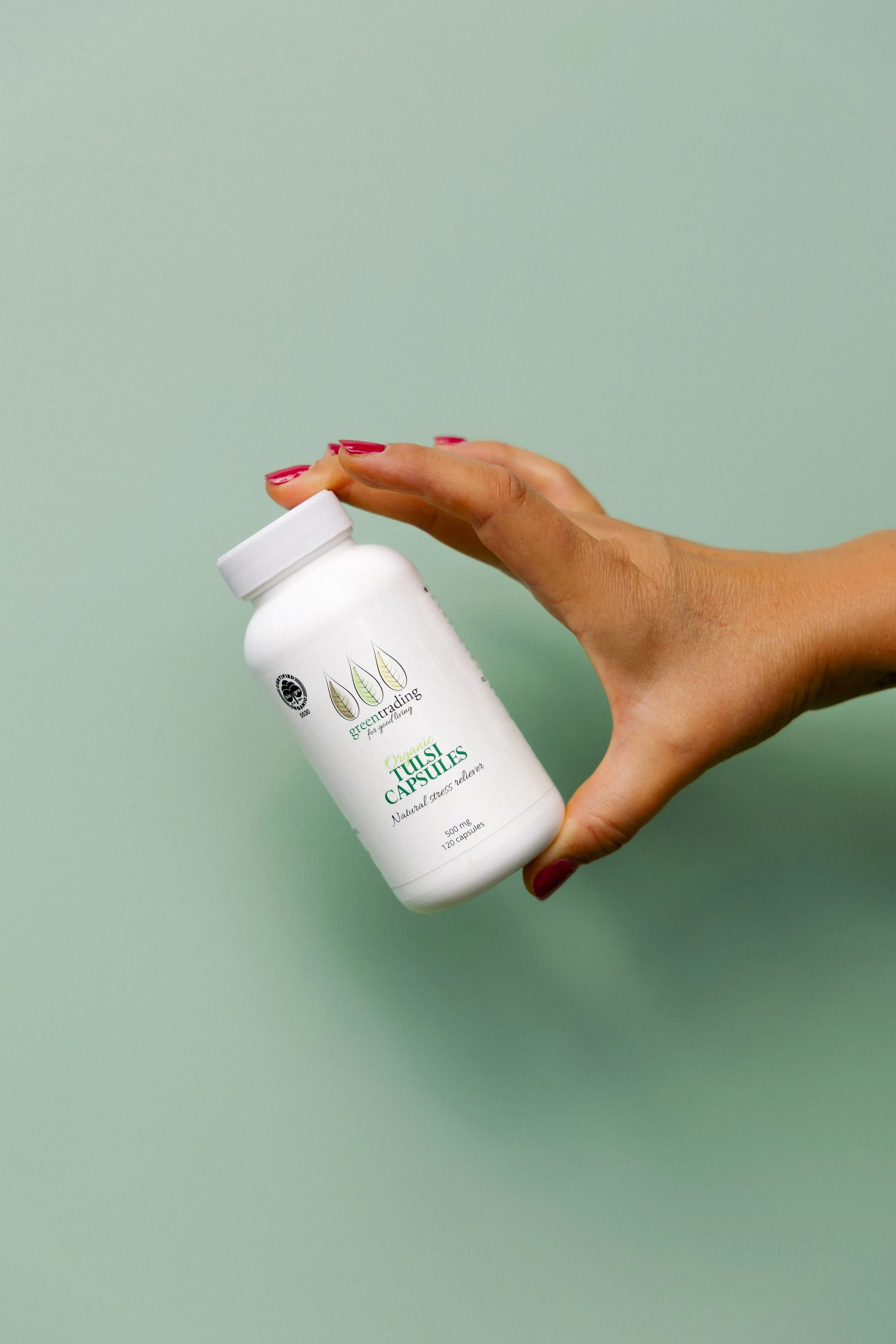 Creative product photography of a Green Trading supplement bottle for social media content creation and brand marketing.