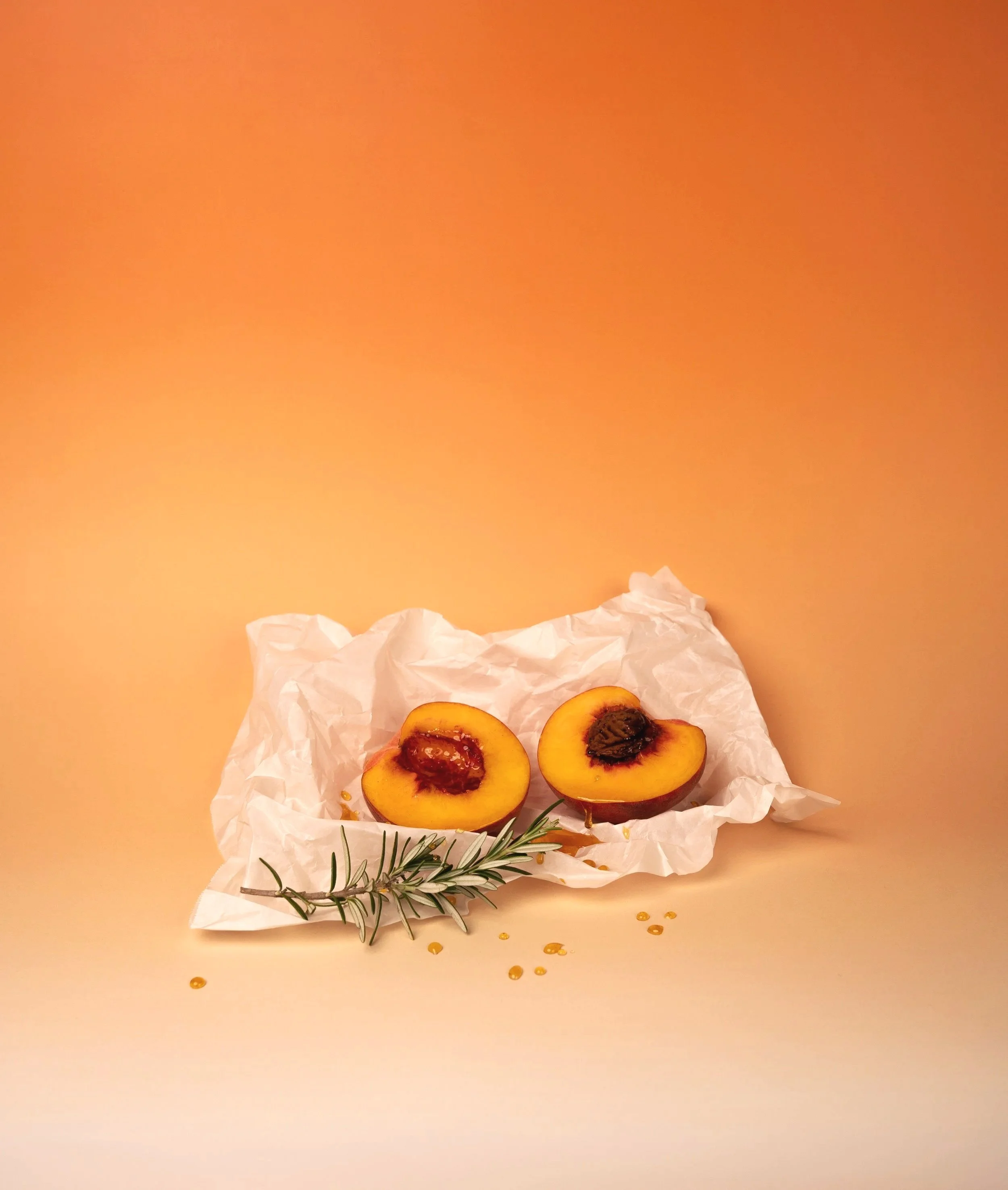 Creative food photography for AHA Honey featuring fresh apricots styled on parchment paper against a vibrant orange background.
