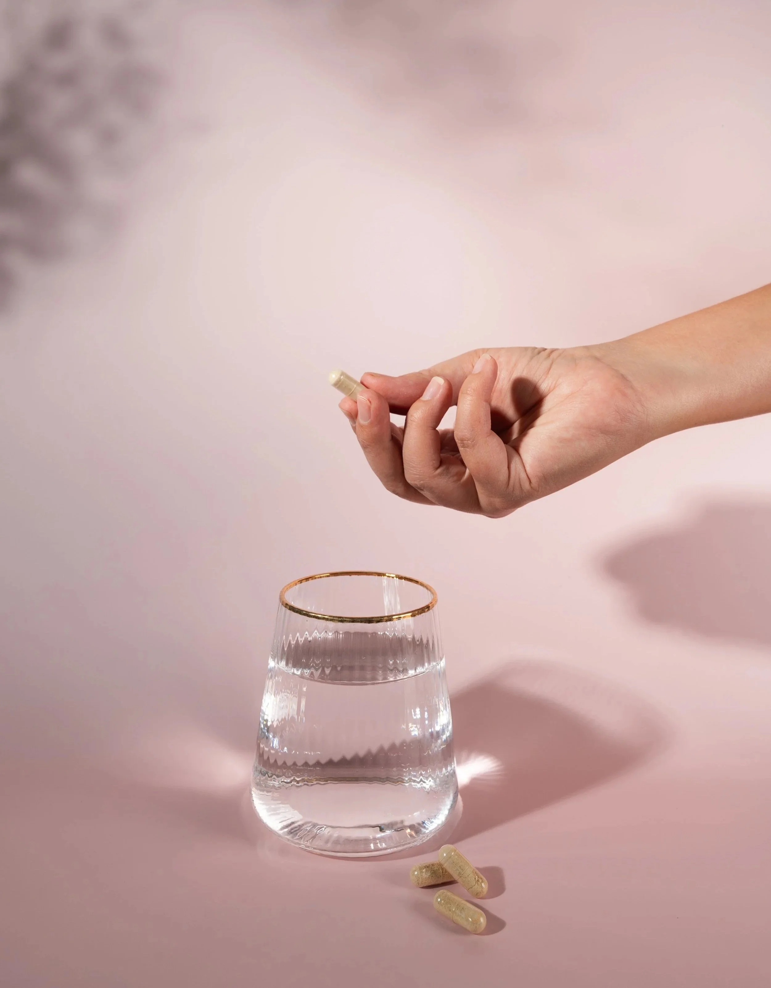 Hand pouring a Green Trading wellness supplement into a glass of water.