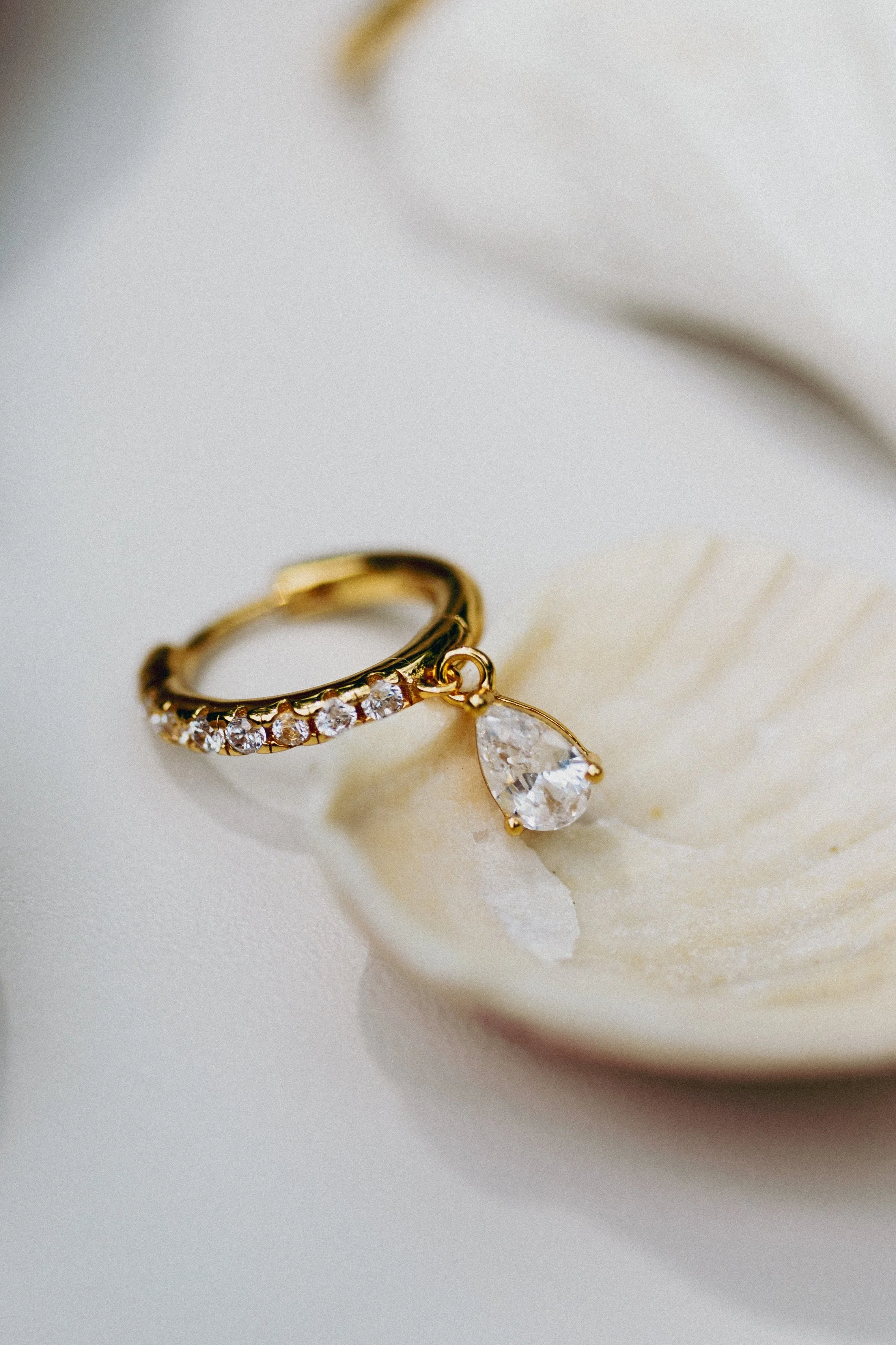Lifestyle jewellery photography for La Dailie featuring a gold ring with a pear-cut gemstone styled in a shell.