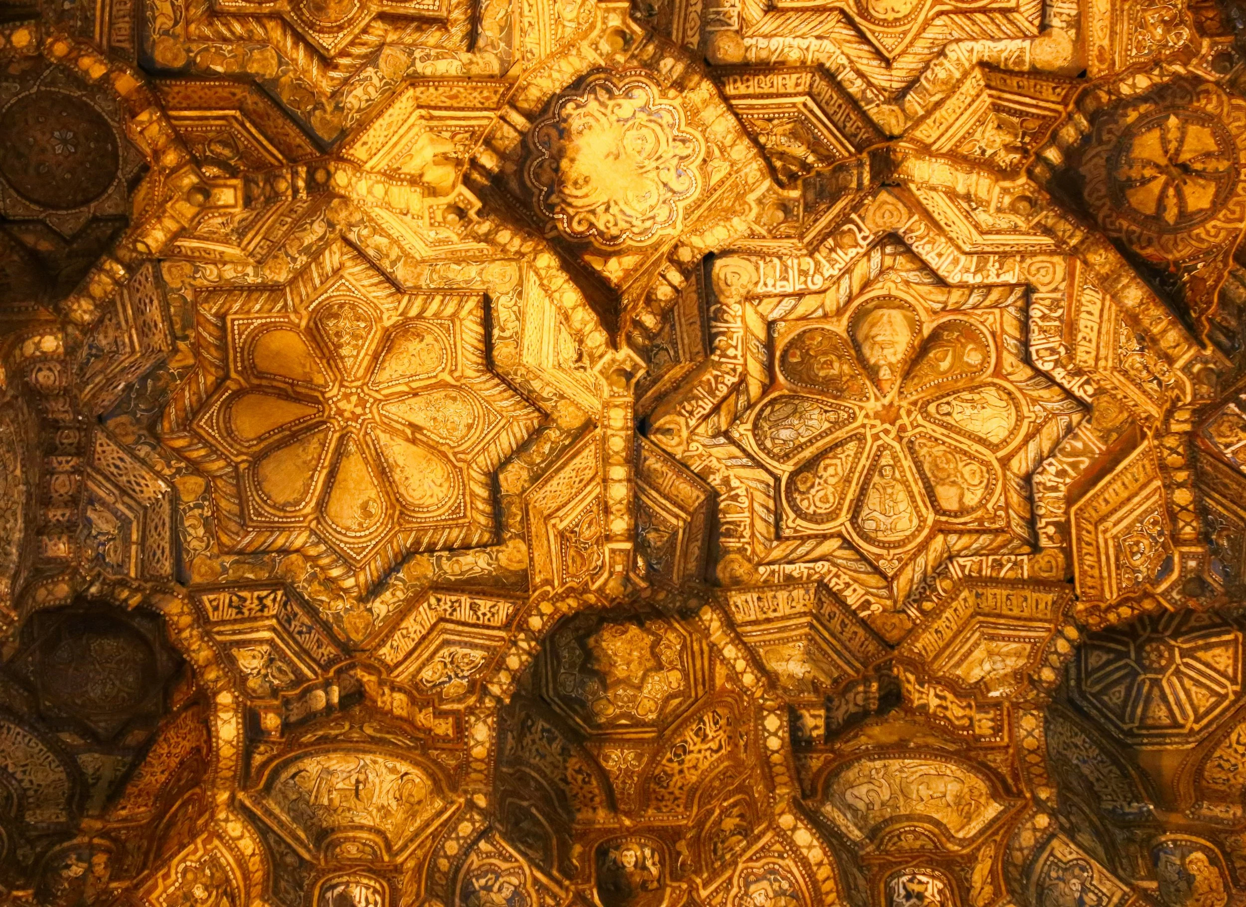 Intricate golden and brown decorated ceiling with geometric and floral patterns.