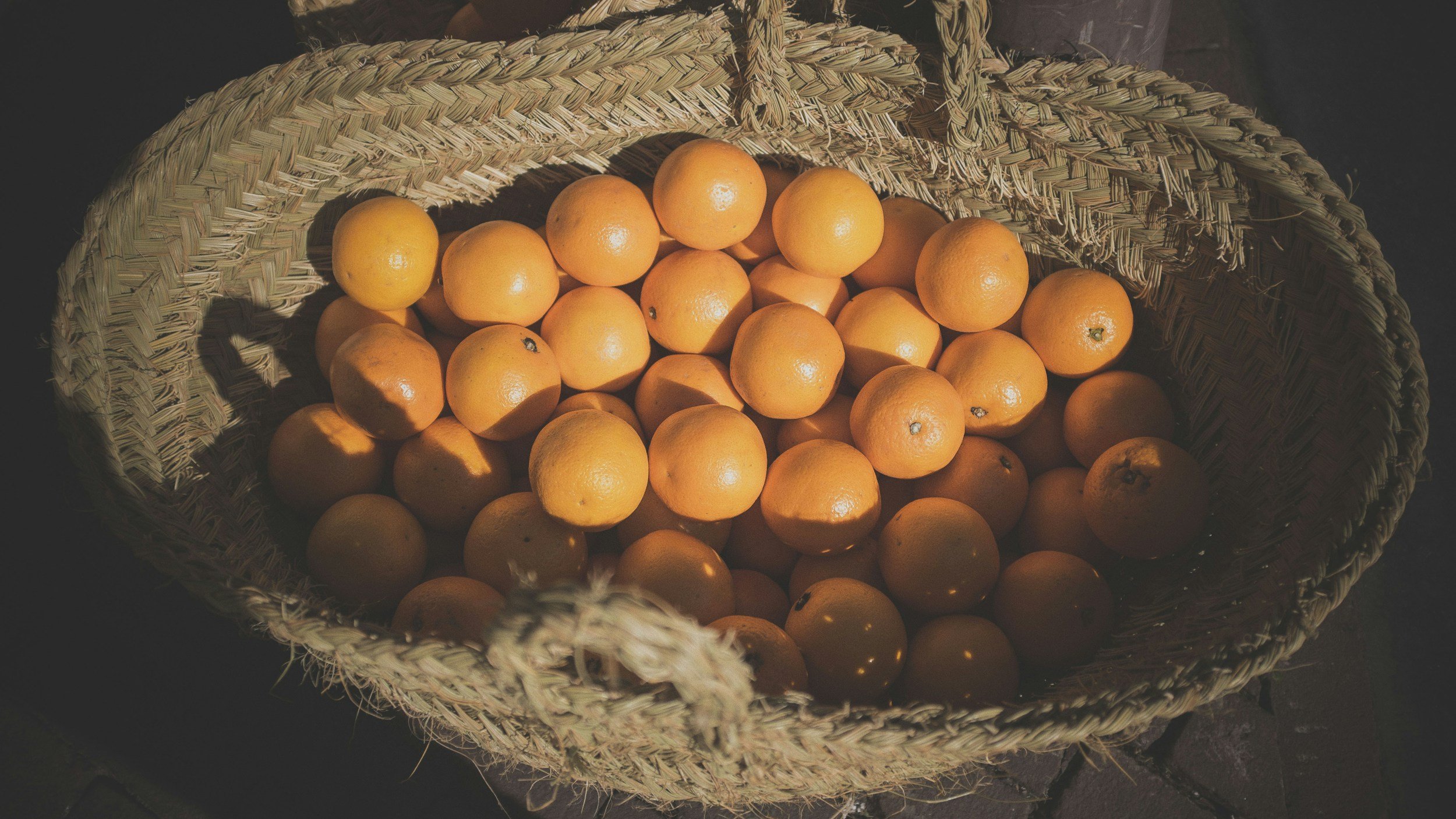 A woven basket filled with oranges.