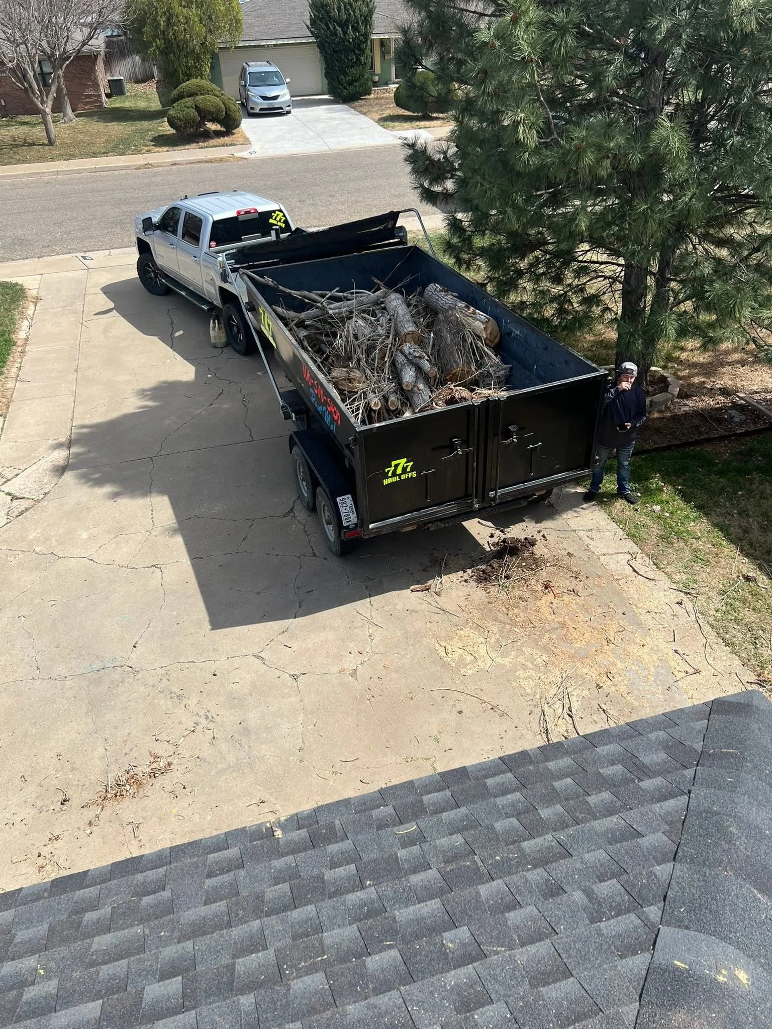 Triple 7 Haul Offs dump trailer loaded with tree limbs and brush in an Amarillo driveway
