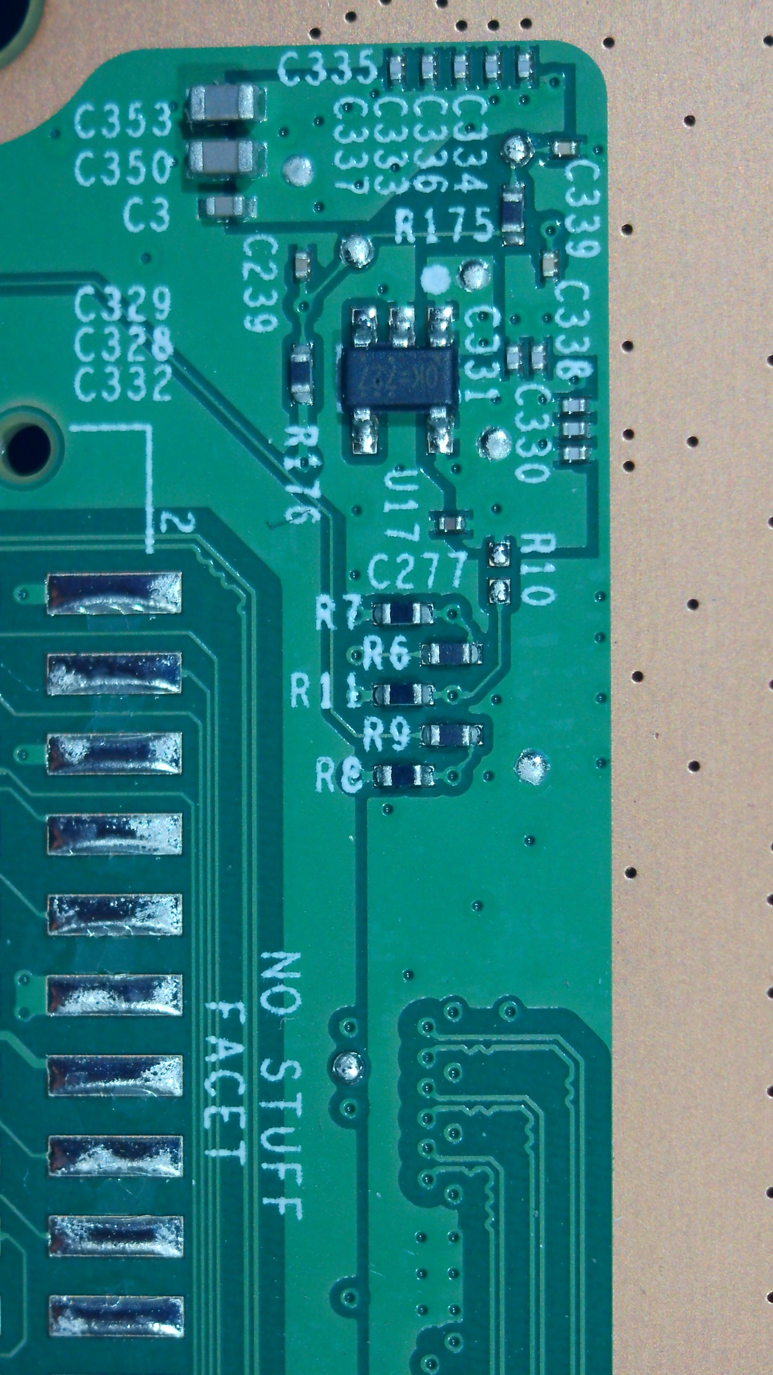 Close-up of a green printed circuit board (PCB) with various electronic components and soldered connections, labeled with white alphanumeric codes.