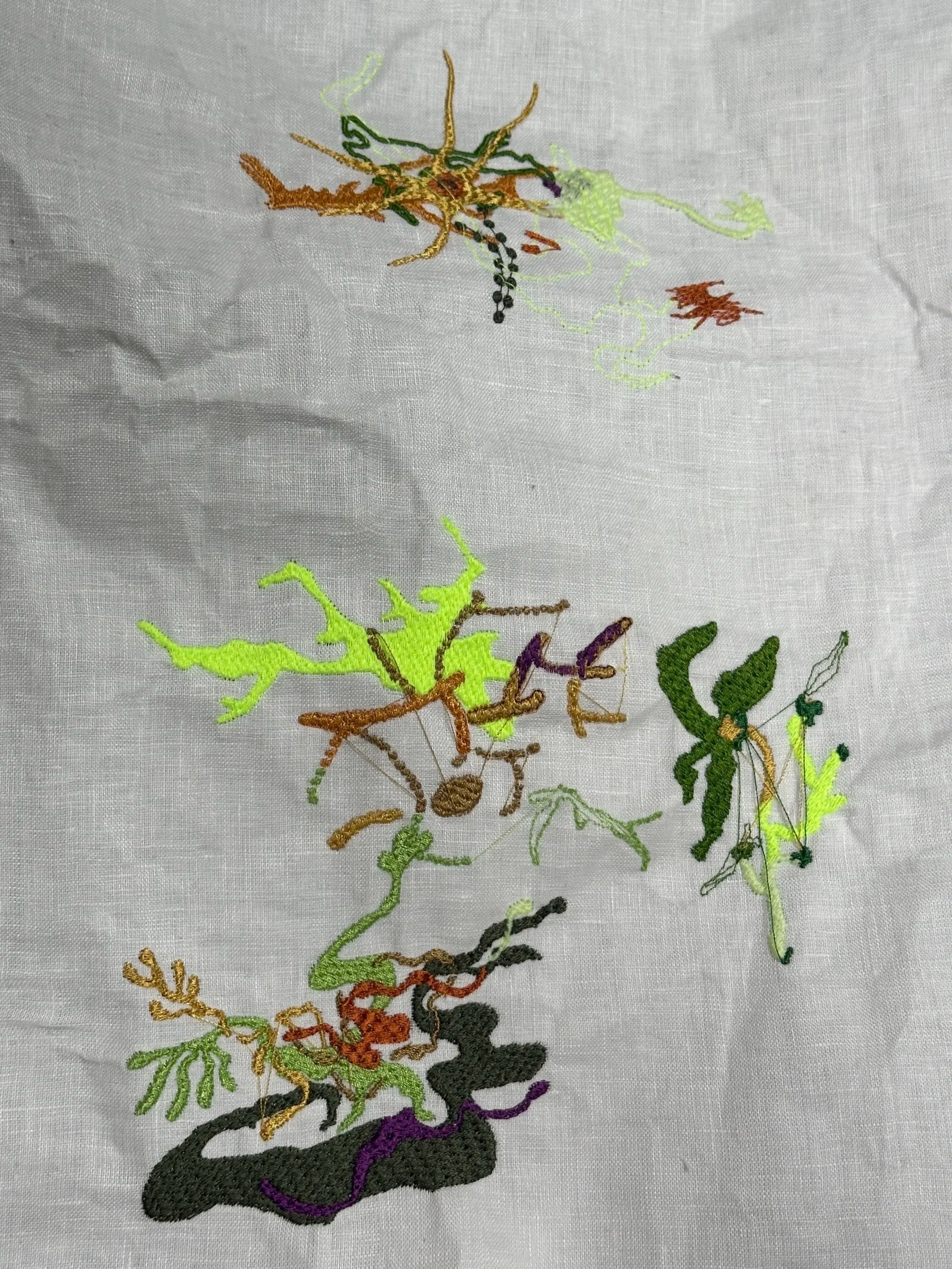 Colorful embroidered outline of a dog with some details and different colors on white fabric.