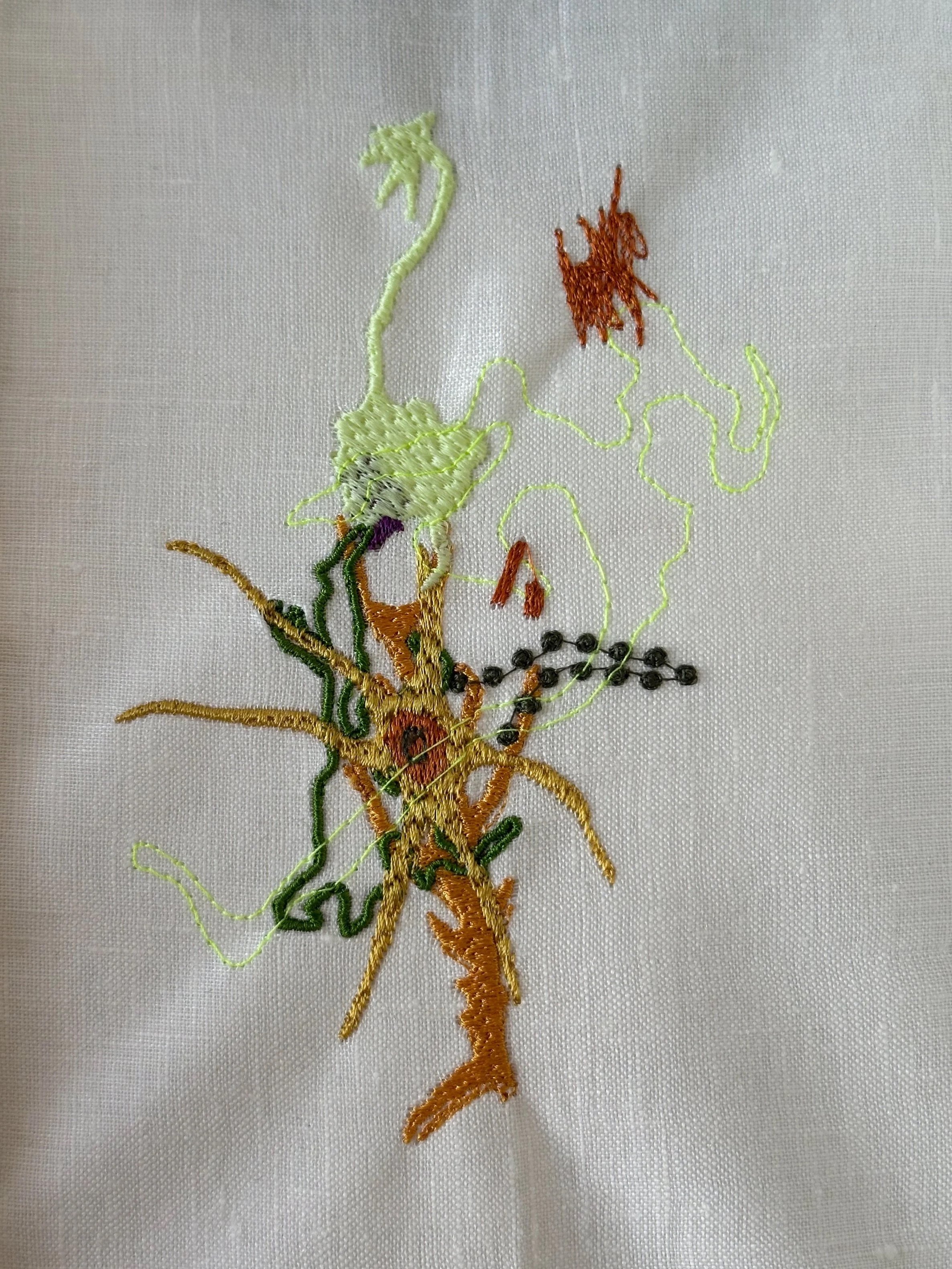 Close-up of colorful embroidered flower on white fabric.