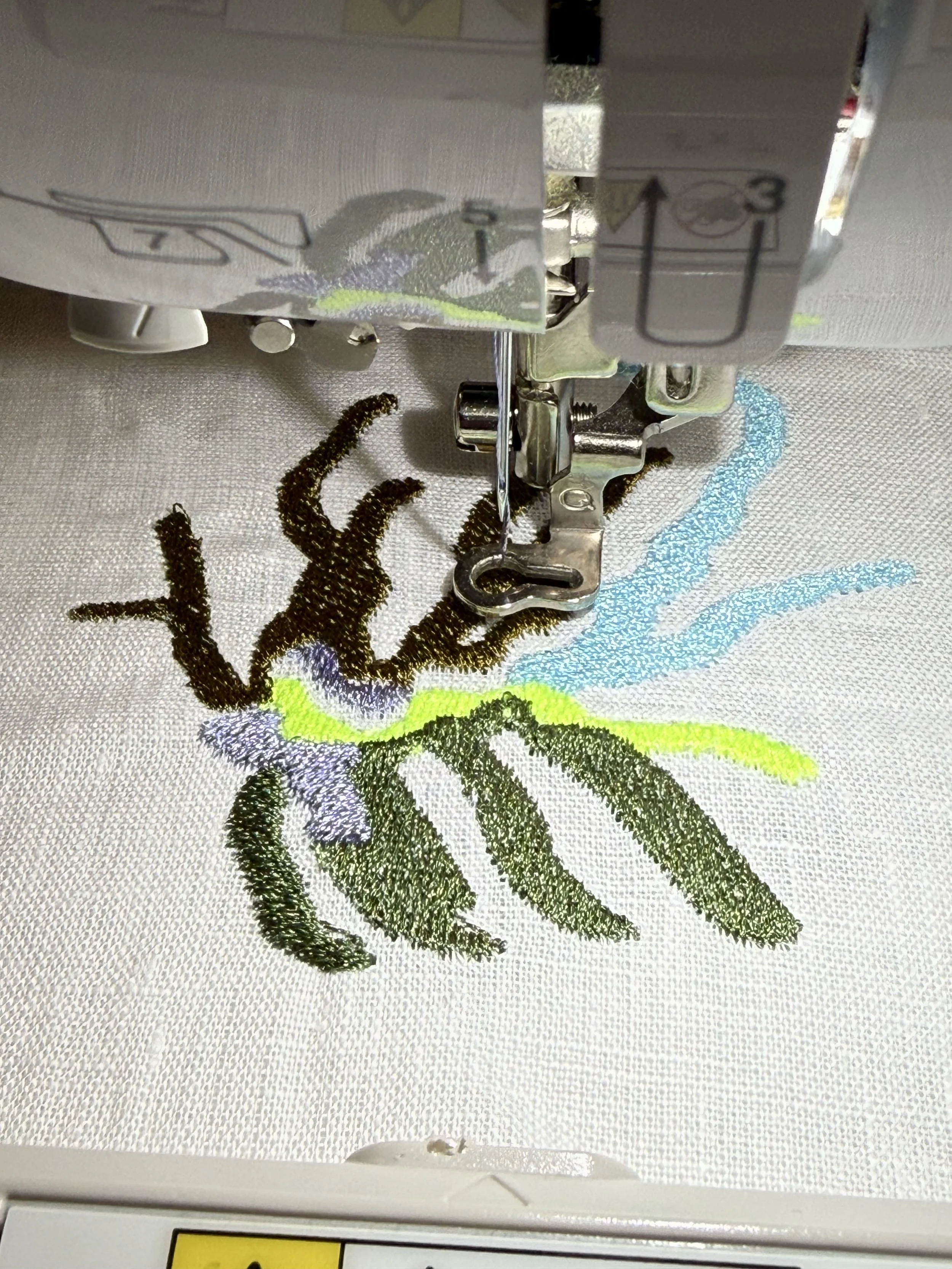 Embroidery machine stitching a colorful floral design on fabric.