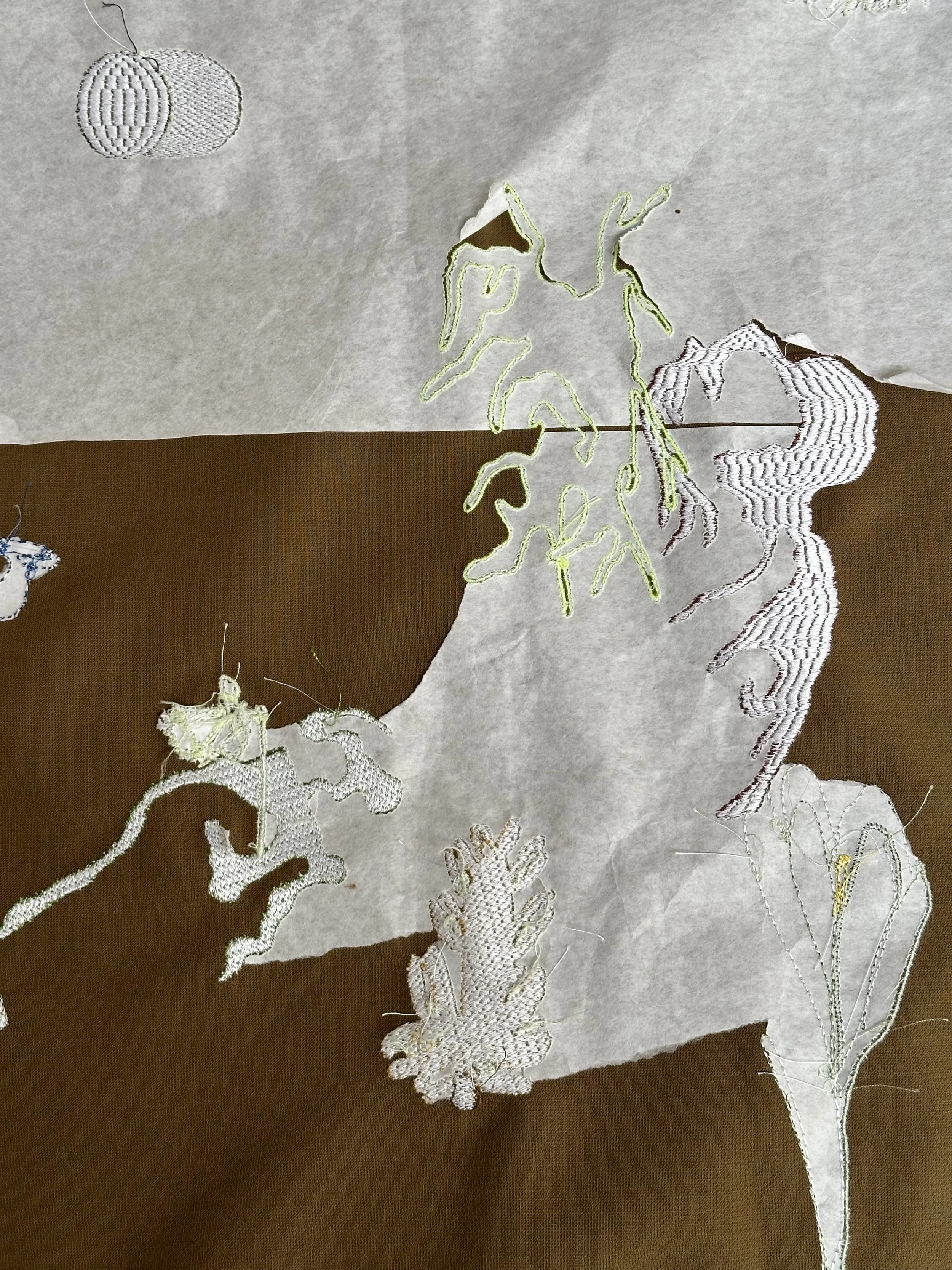 Close-up of white lace embroidery on fabric, featuring floral and leaf designs with intricate details.