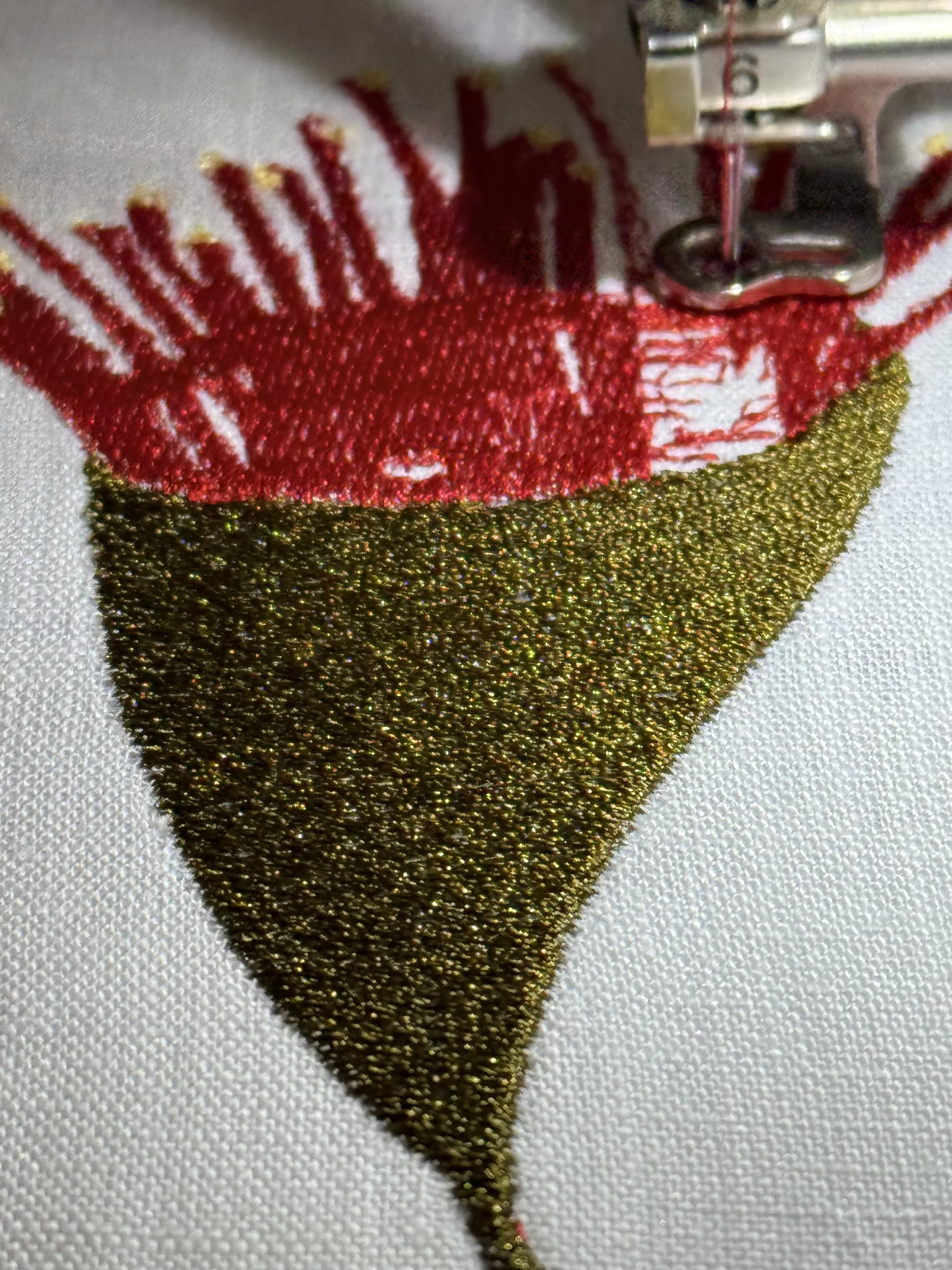Close-up of embroidery sewing on fabric, with red and gold thread.