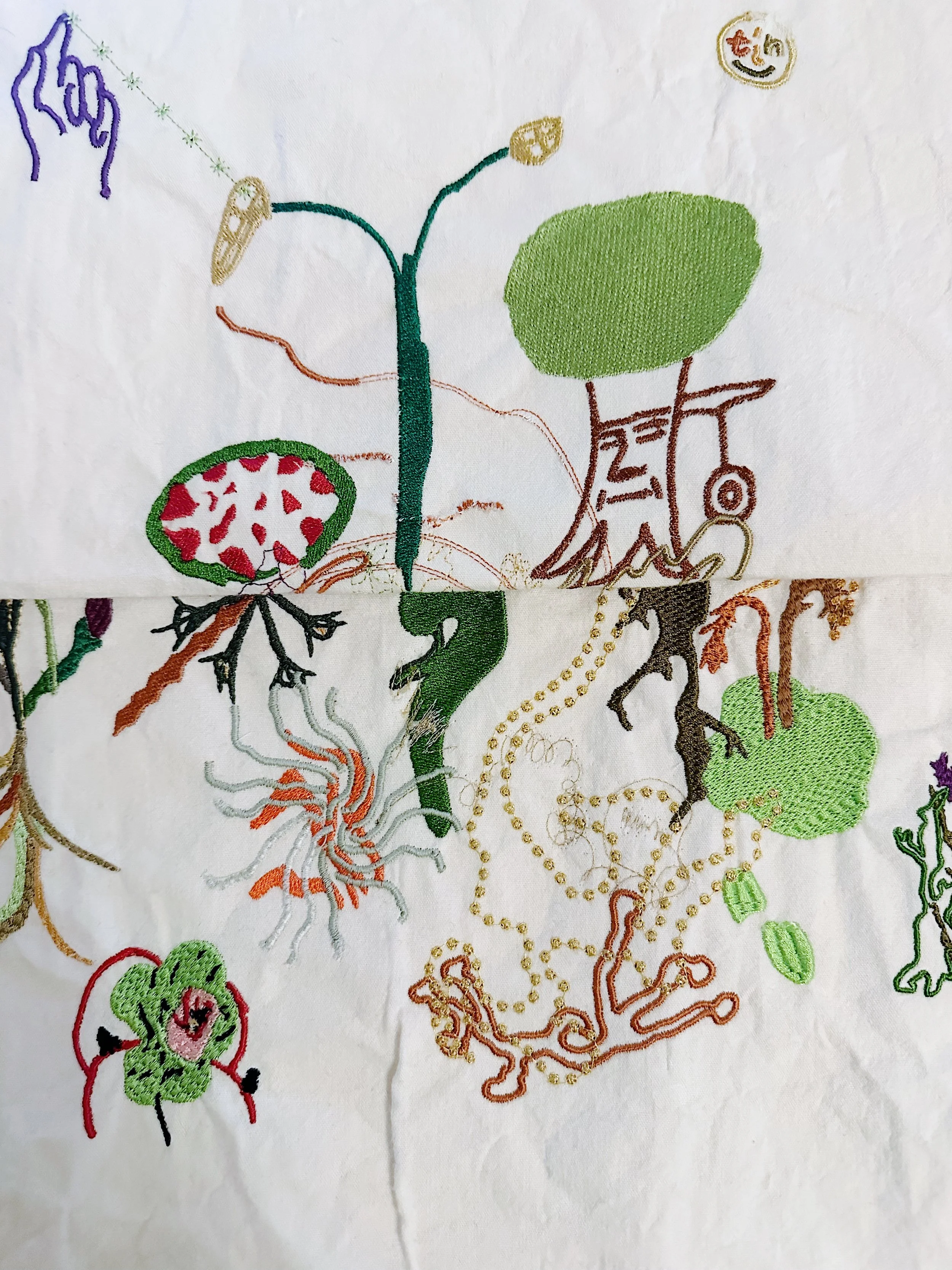 Embroidery of various colorful roots, plants, and fruits on white fabric.