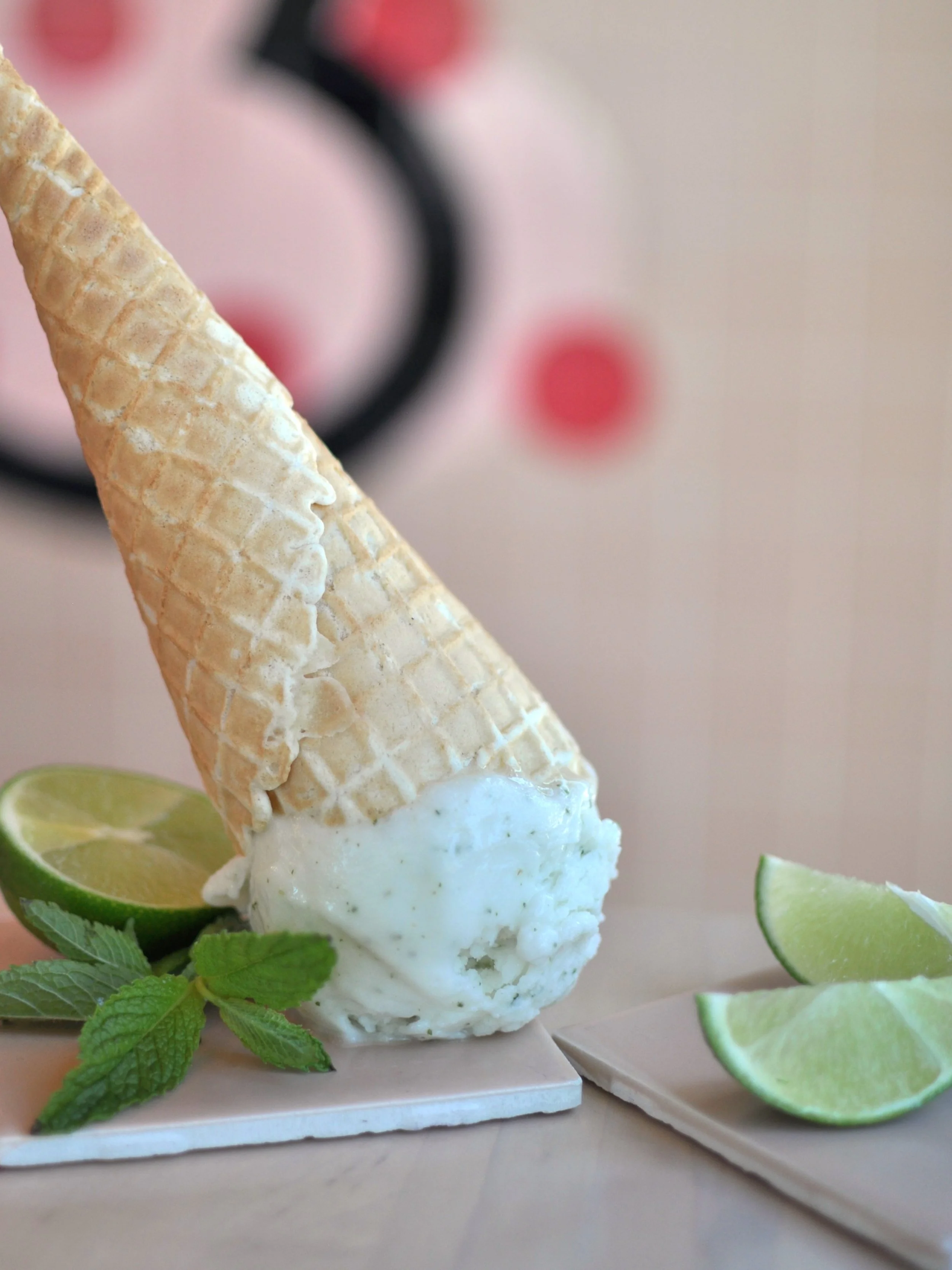 Upside down ice cream cone of the Mojito Sorbet flavour with mint leaves and lime slices.