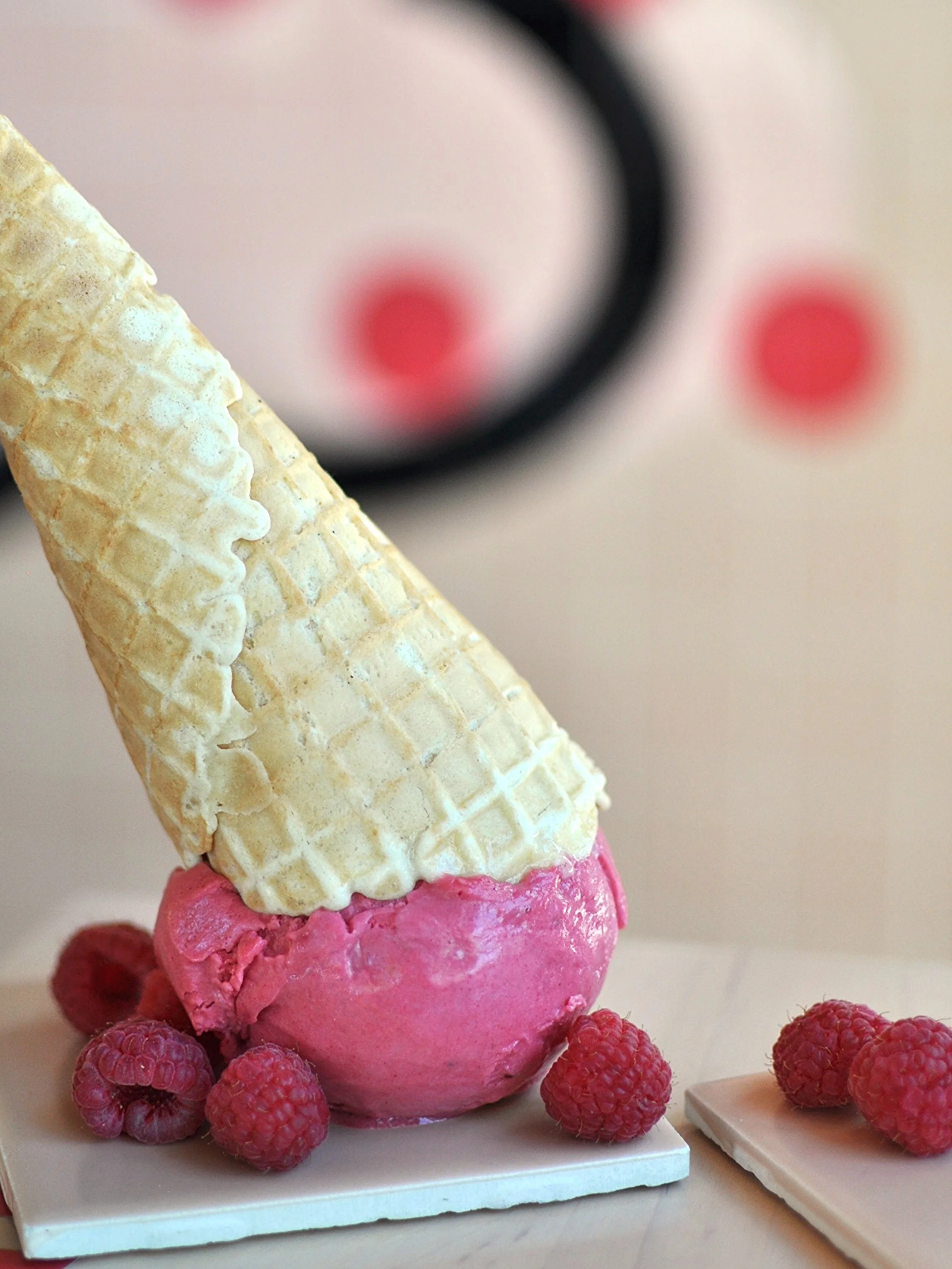 Upside down ice cream cone of the Raspberry Sorbet flavour with fresh raspberries.