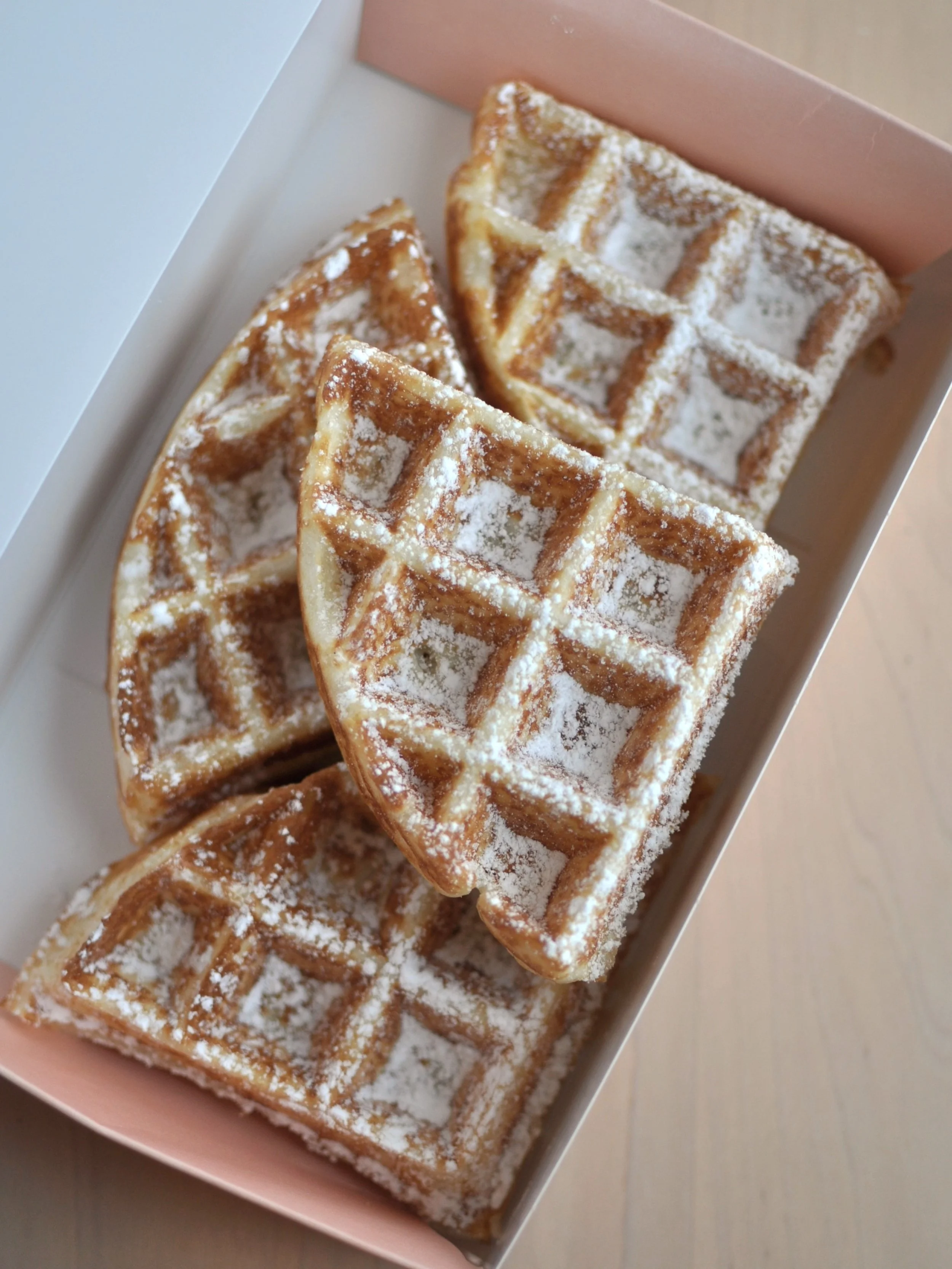 Four slices of Belgium waffle with powered sugar on top