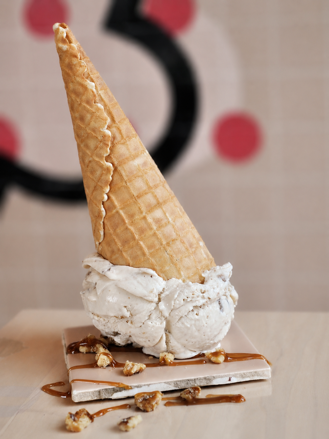 Upside down ice cream cone of the Maple Walnut flavour with drizzle of maple syrup and bits of walnuts.