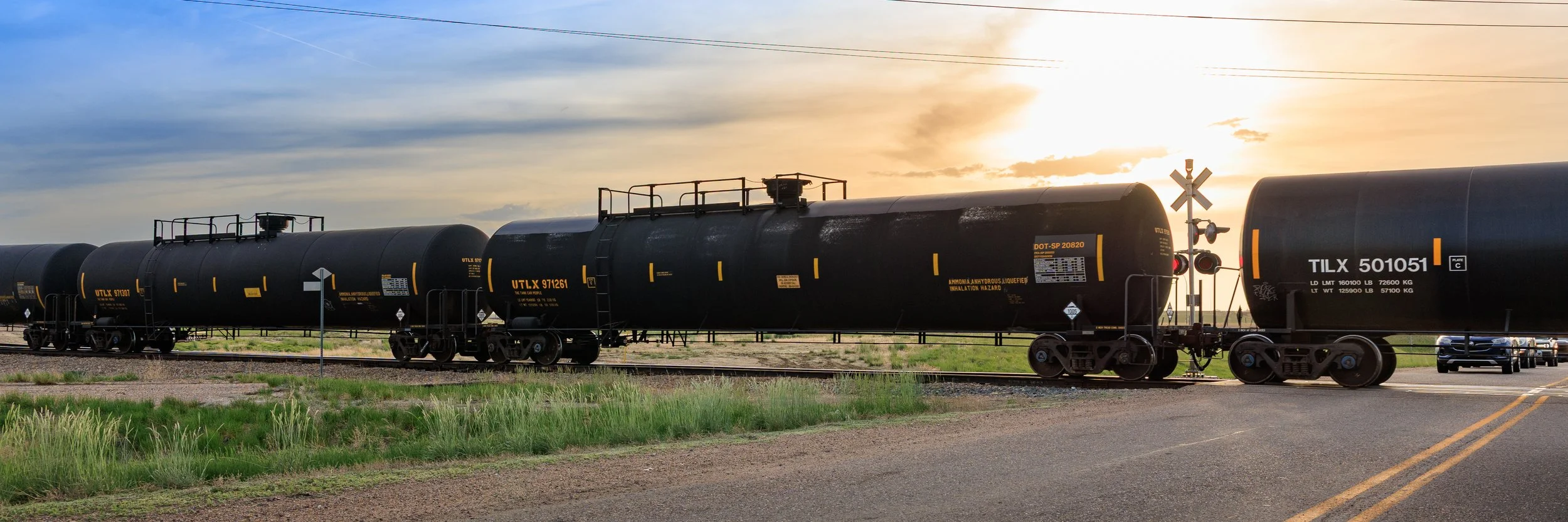 Black tanker train cars on tracks during sunset.