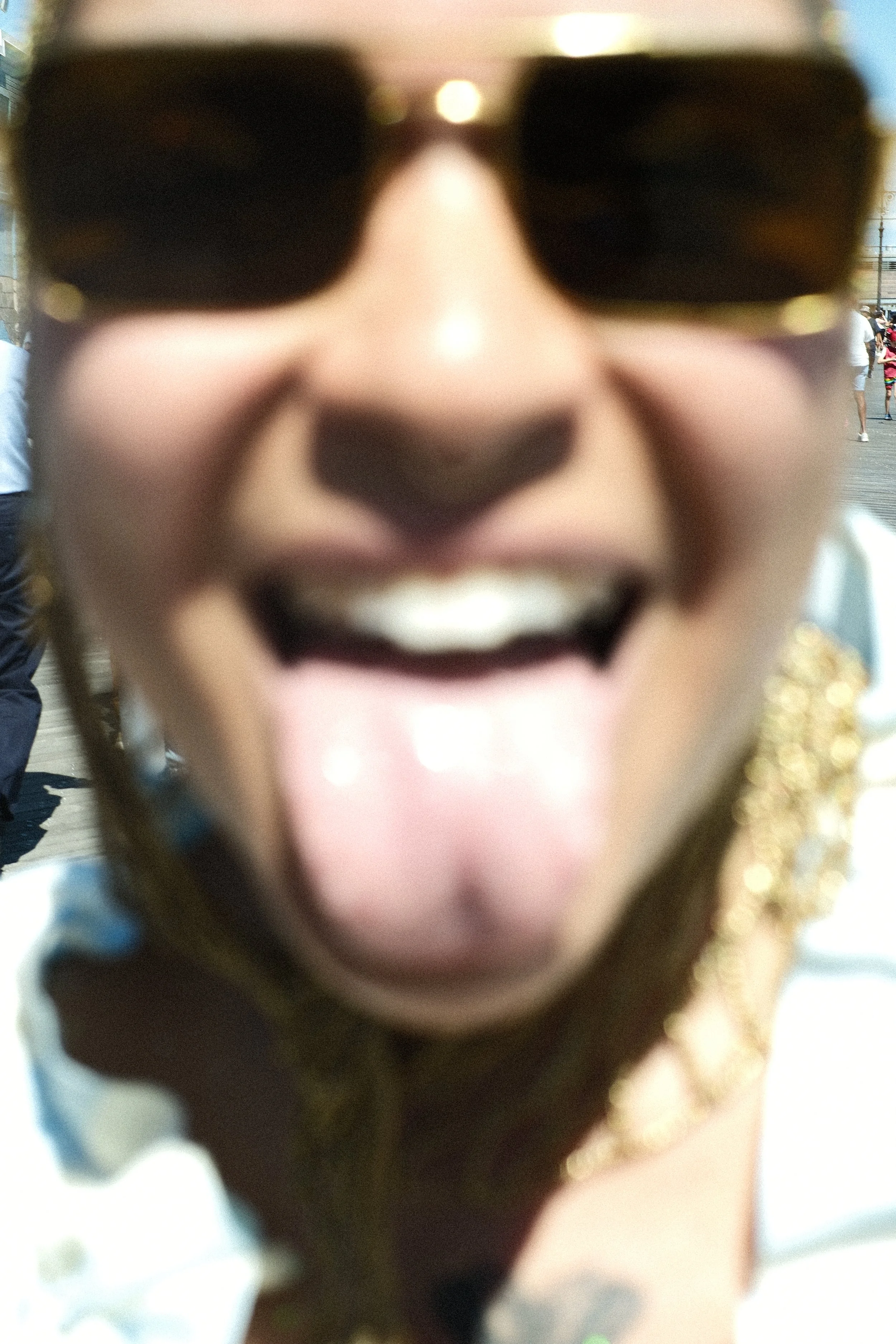 Close-up of a smiling person wearing sunglasses at an outdoor event.