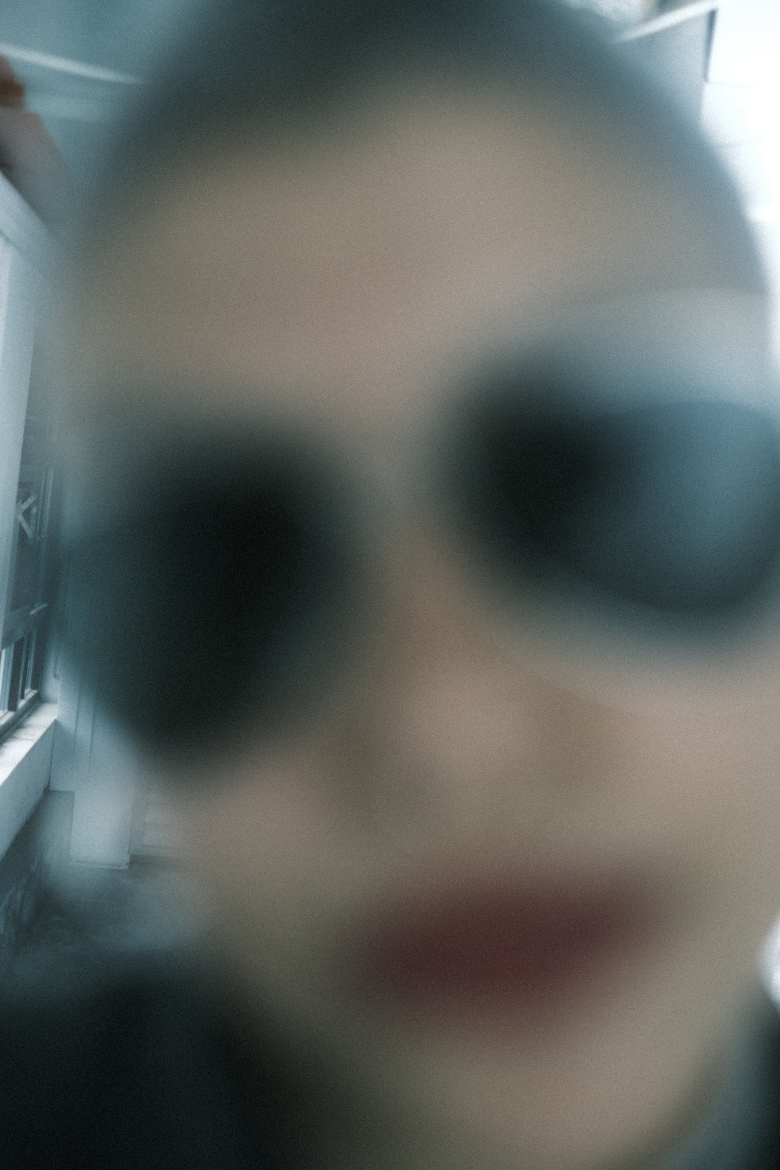 Blurred indoor scene with window on the left side and dark objects in the center.