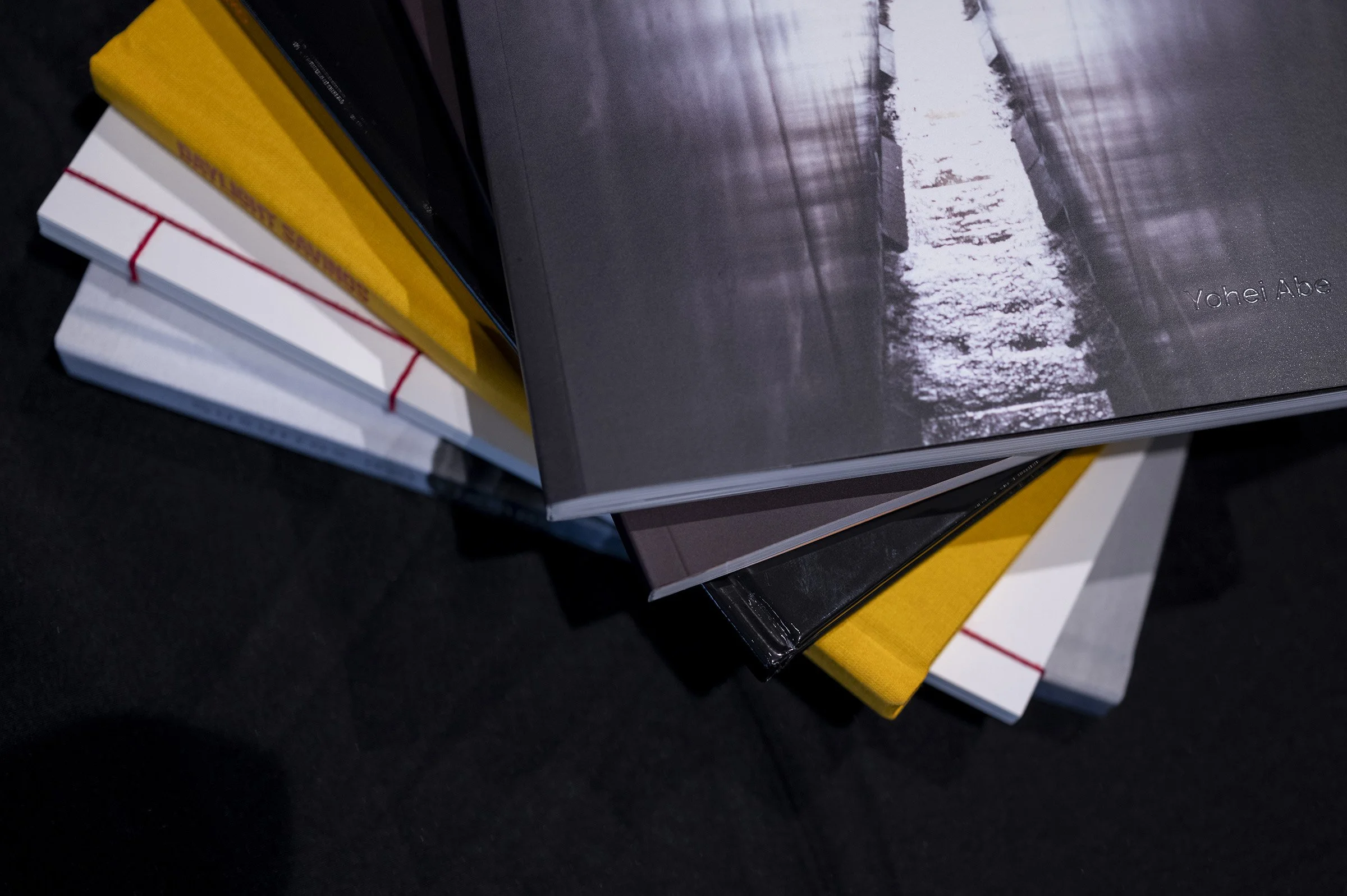 A stack of books with colorful covers and white elastic bands on a black surface.