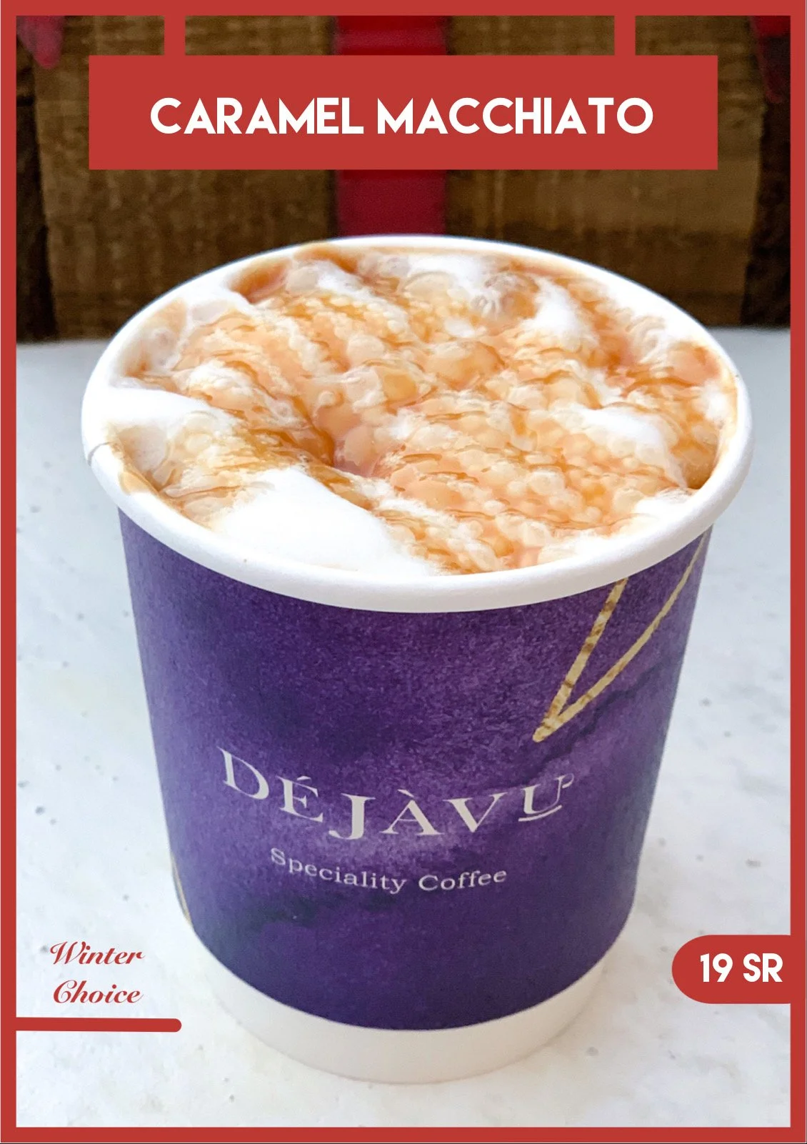 A cup of caramel macchiato with foam and caramel drizzle in a purple cup with the brand DEJAVU written on it, placed on a white surface.