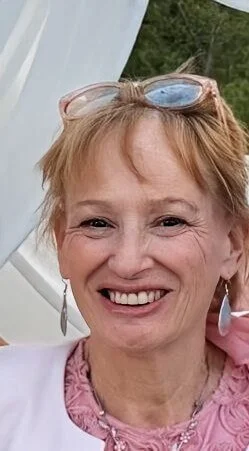 Tess profile picture smiling wearing a white jumper and earrings