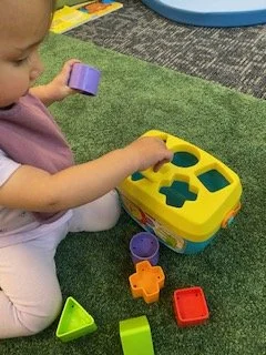 Child playing with colorful toy shape sorter on grass