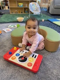 Baby girl sitting on the floor playing with a toy keyboard