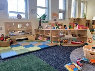 Child's playroom with soft foam mats, books, and toys on shelves and the floor