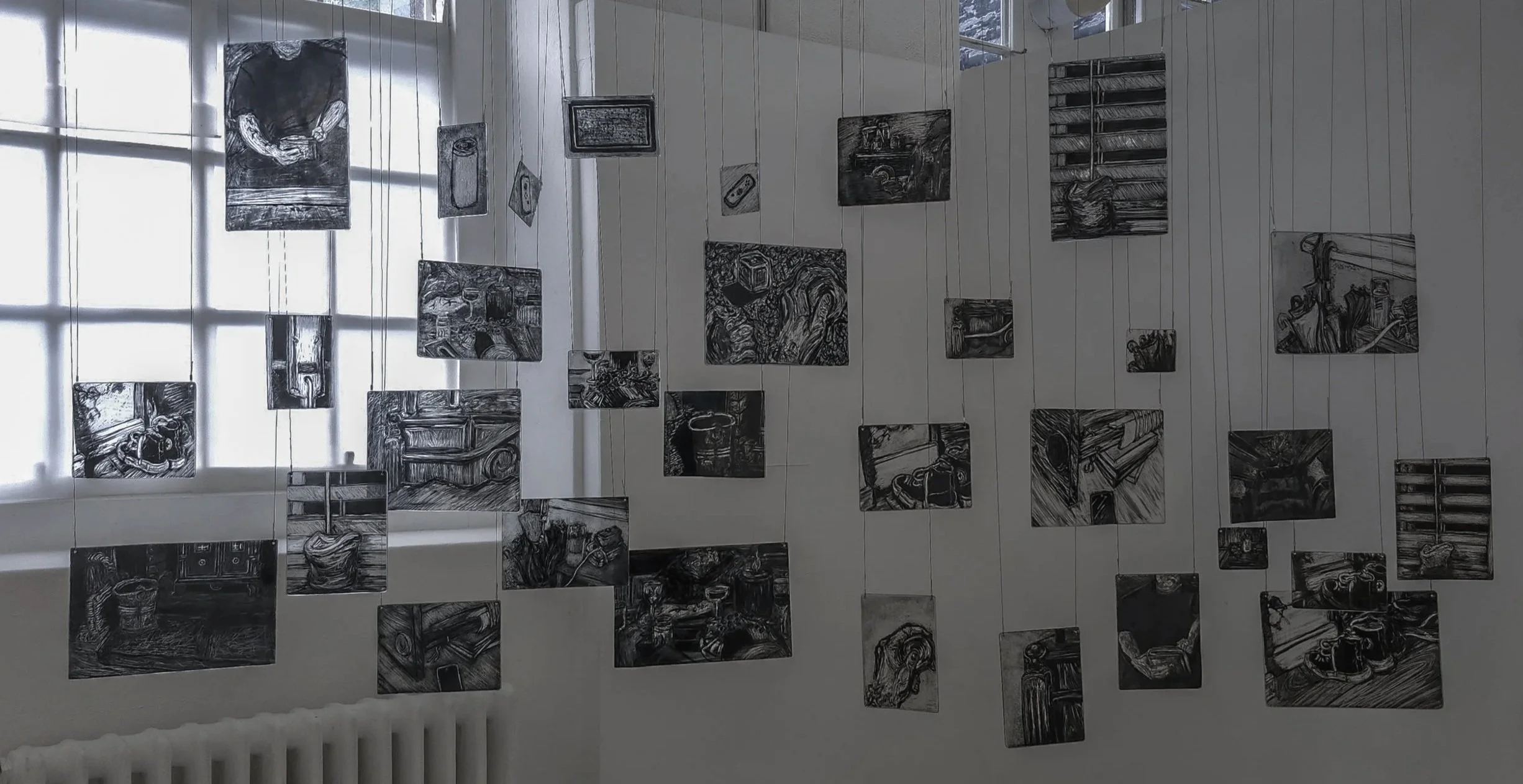 32 glass pieces ranging from a6 to a4 in size with sgraffito paintings depicting day to day moments in a sort of memory mobile