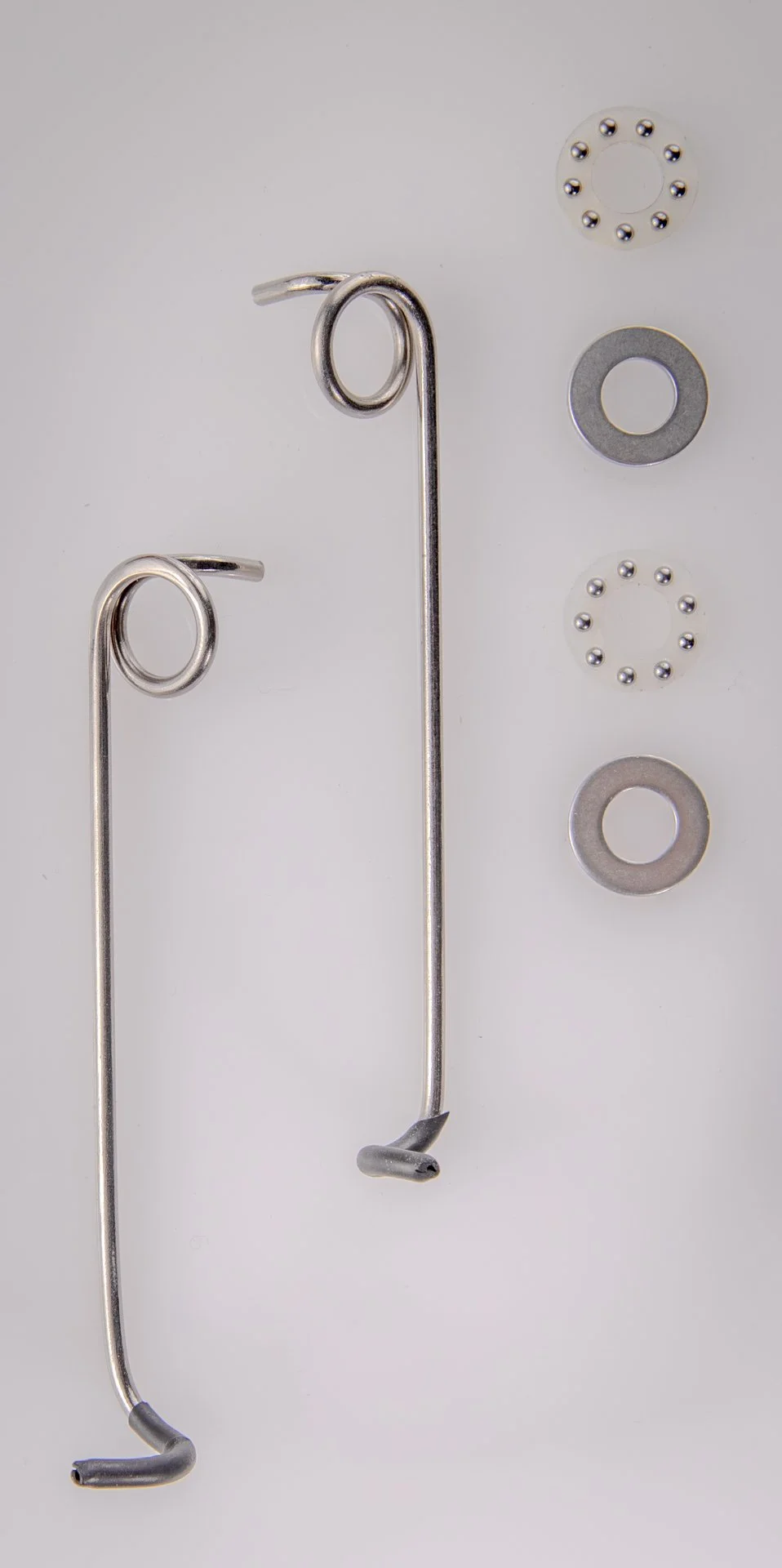 Metal mechanical clips, washers, and ball bearings on a white background.