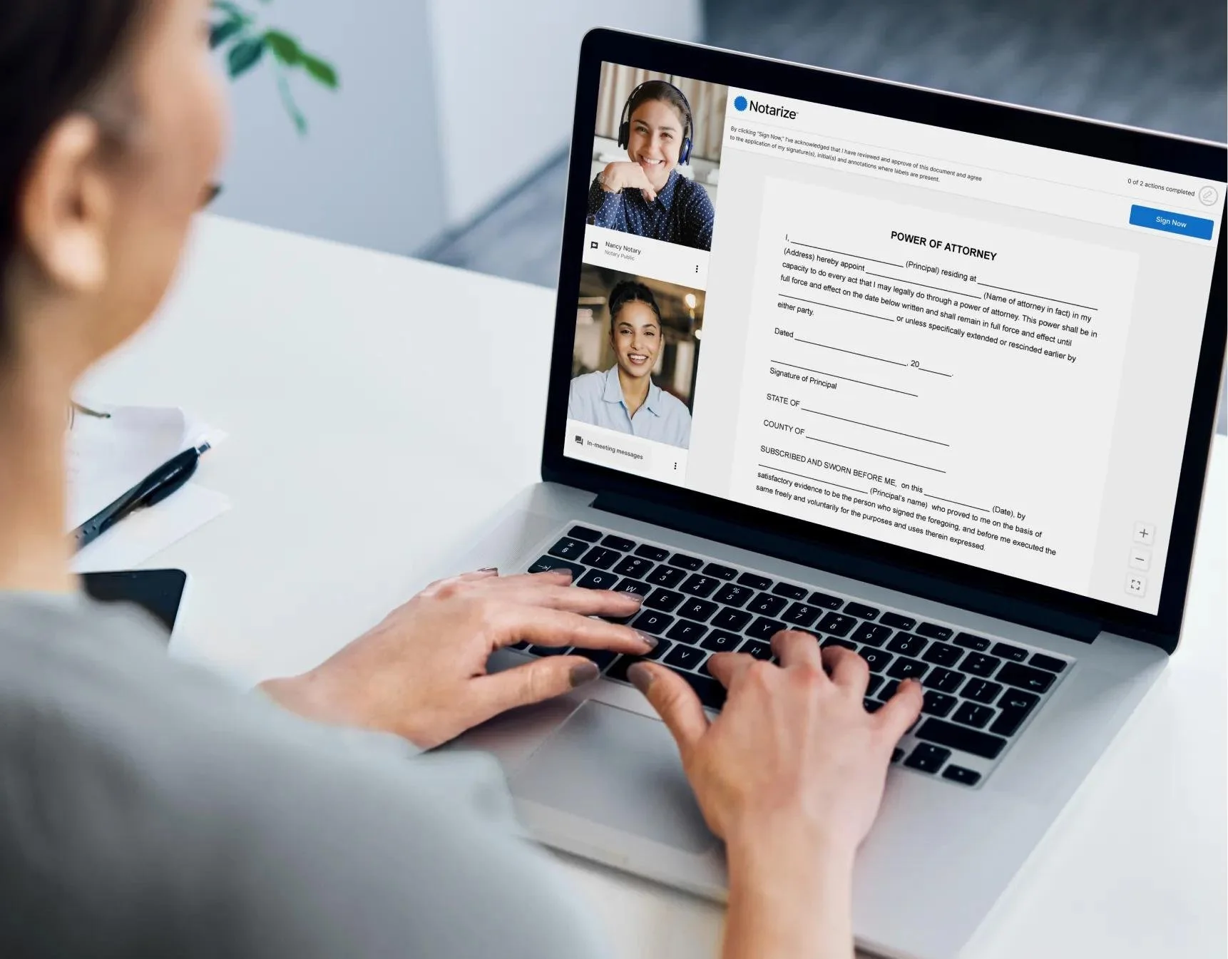 Person participating in virtual notary signing on a laptop with two video call participants displayed and the notary document on the screen.