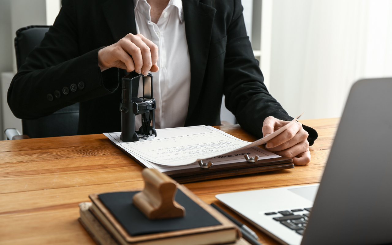 Person, possibility a notary, stamping a document at a desk.