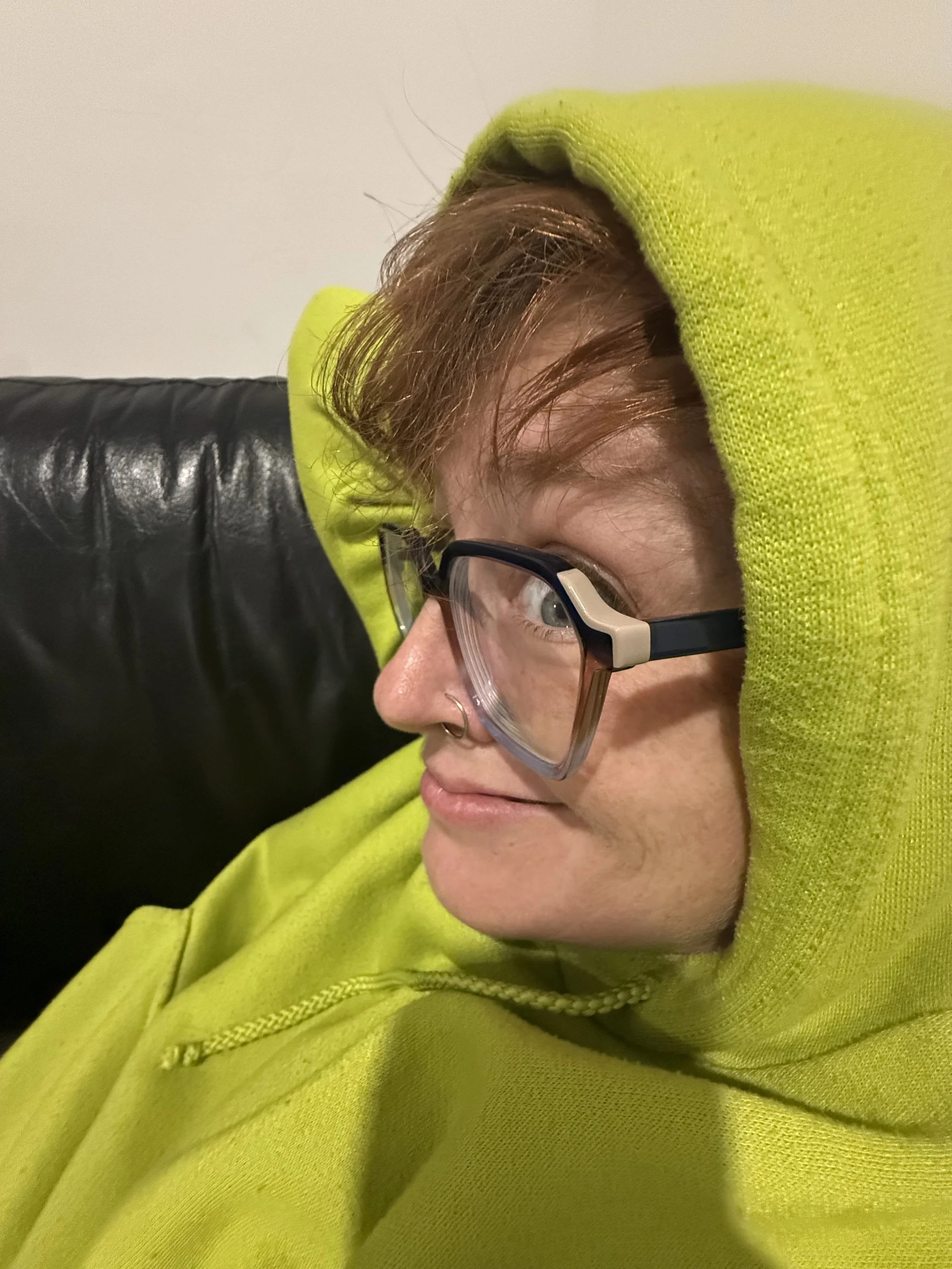 Close-up of a woman's face. She's wearing glasses and a bright yellow hoodie, and she's giving the camera major side-eye.