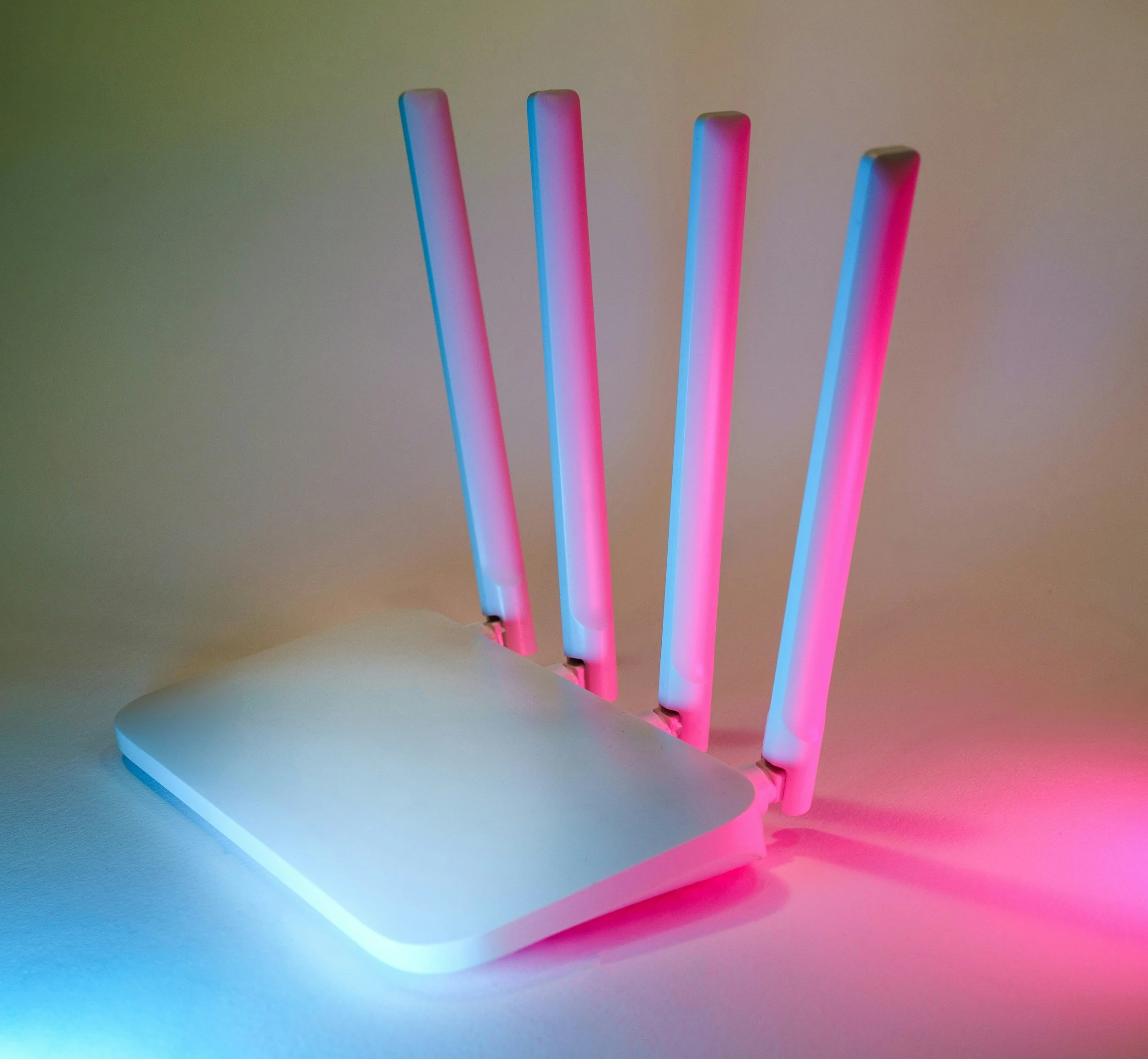 Colorful LED light sticks emitting pink, blue, and purple illumination on a light-colored surface and wall.