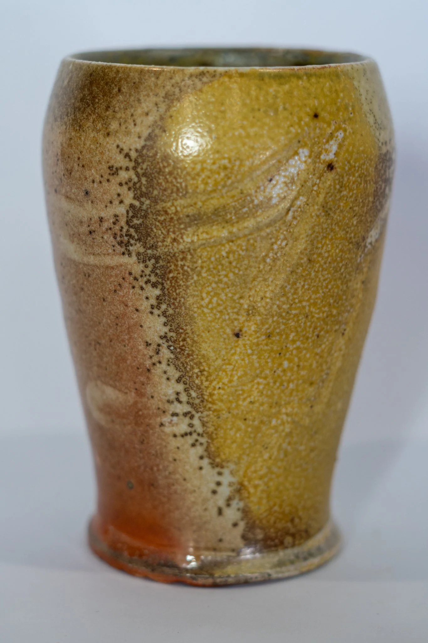 A ceramic vase featuring a textured and multicolored glaze in earthy tones of yellow, brown, and orange.
