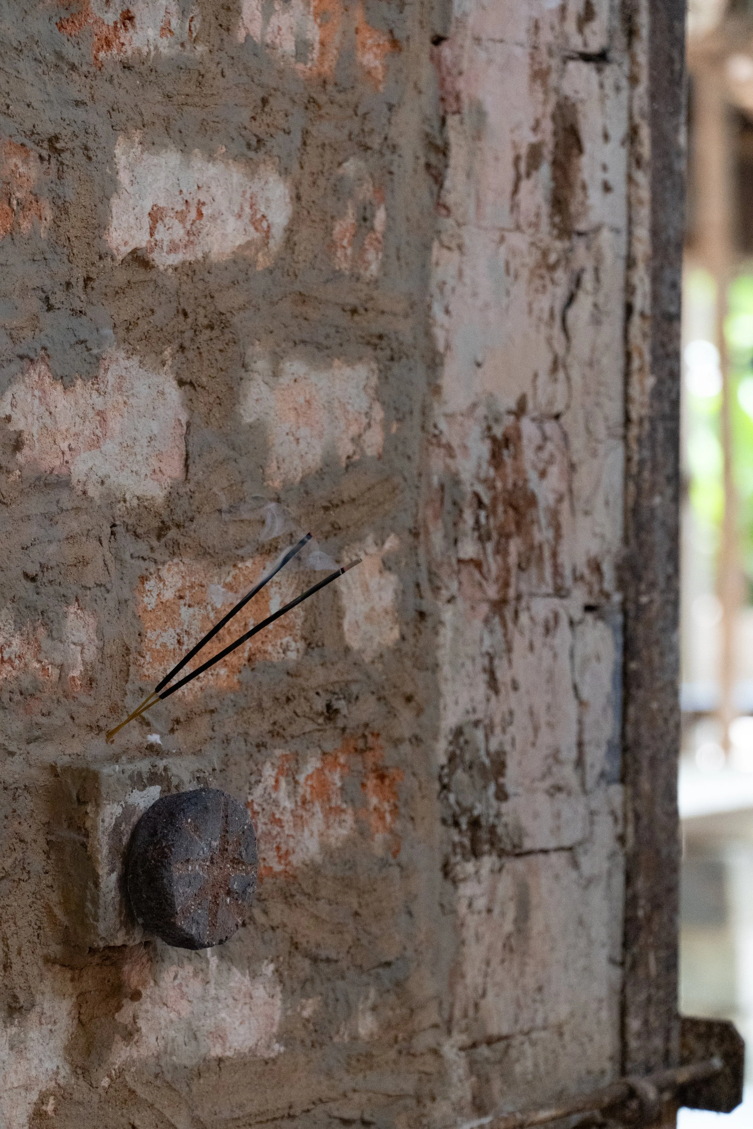 Close-up of an old, weathered brick wall with some exposed wiring and an electrical outlet.