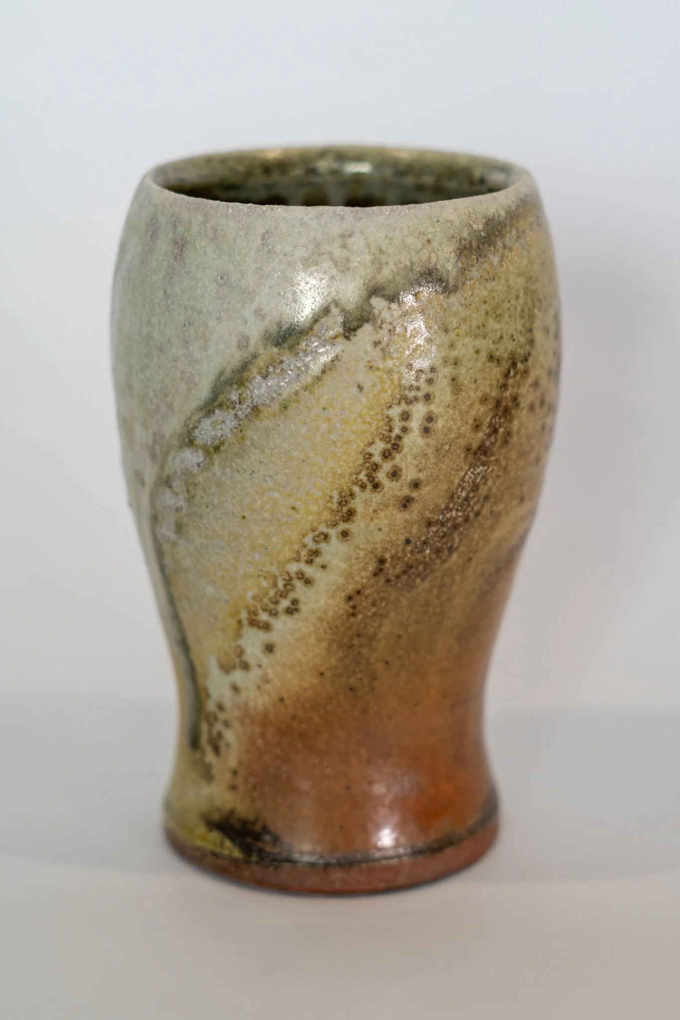 A ceramic vase with abstract glaze design in earthy tones, featuring a narrow base and wider top.