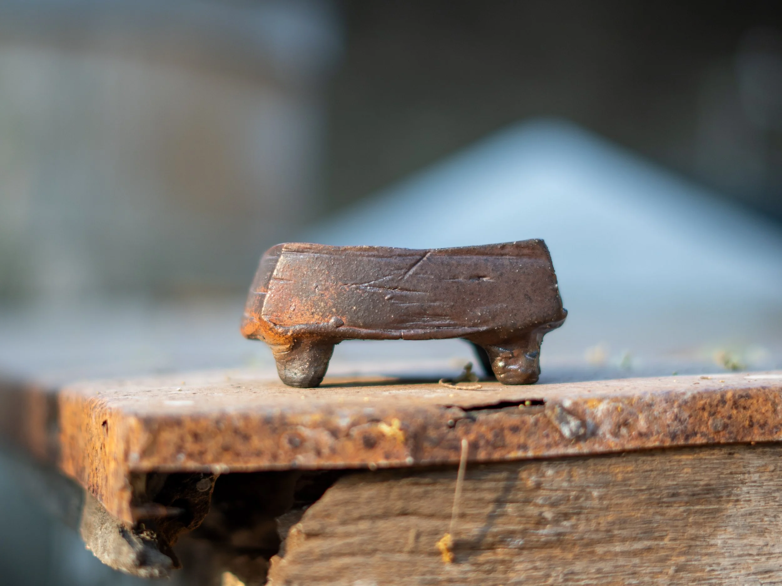 Close-up of a rusty, aged metal bench with a dark, blurred background.