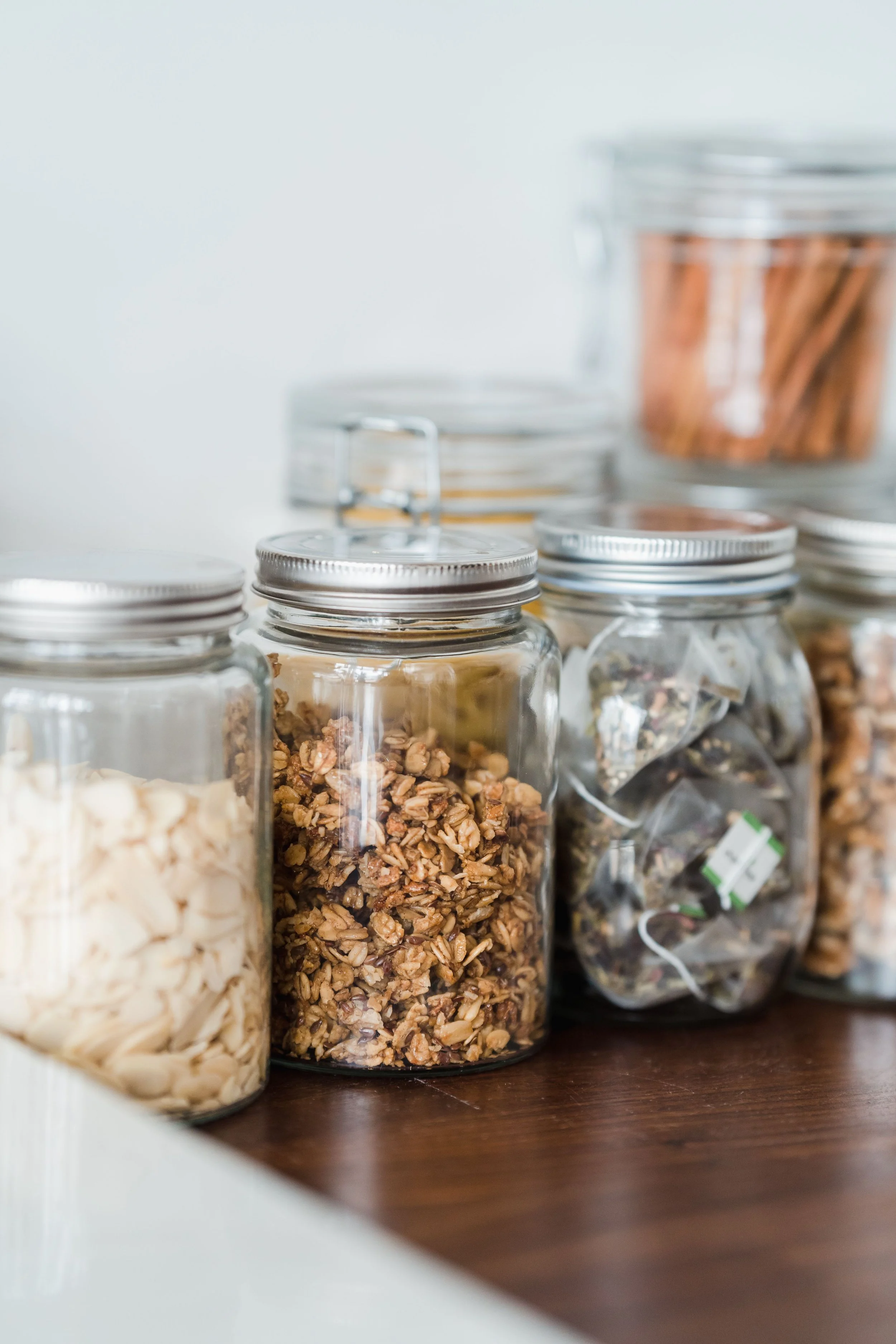 Various jars filled with different types of dried goods placed on a dark wooden surface.