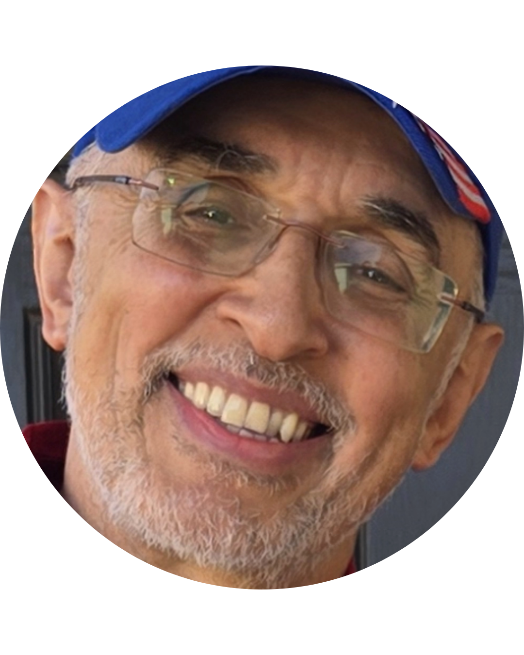 Close-up of smiling elderly man wearing glasses and a blue cap.