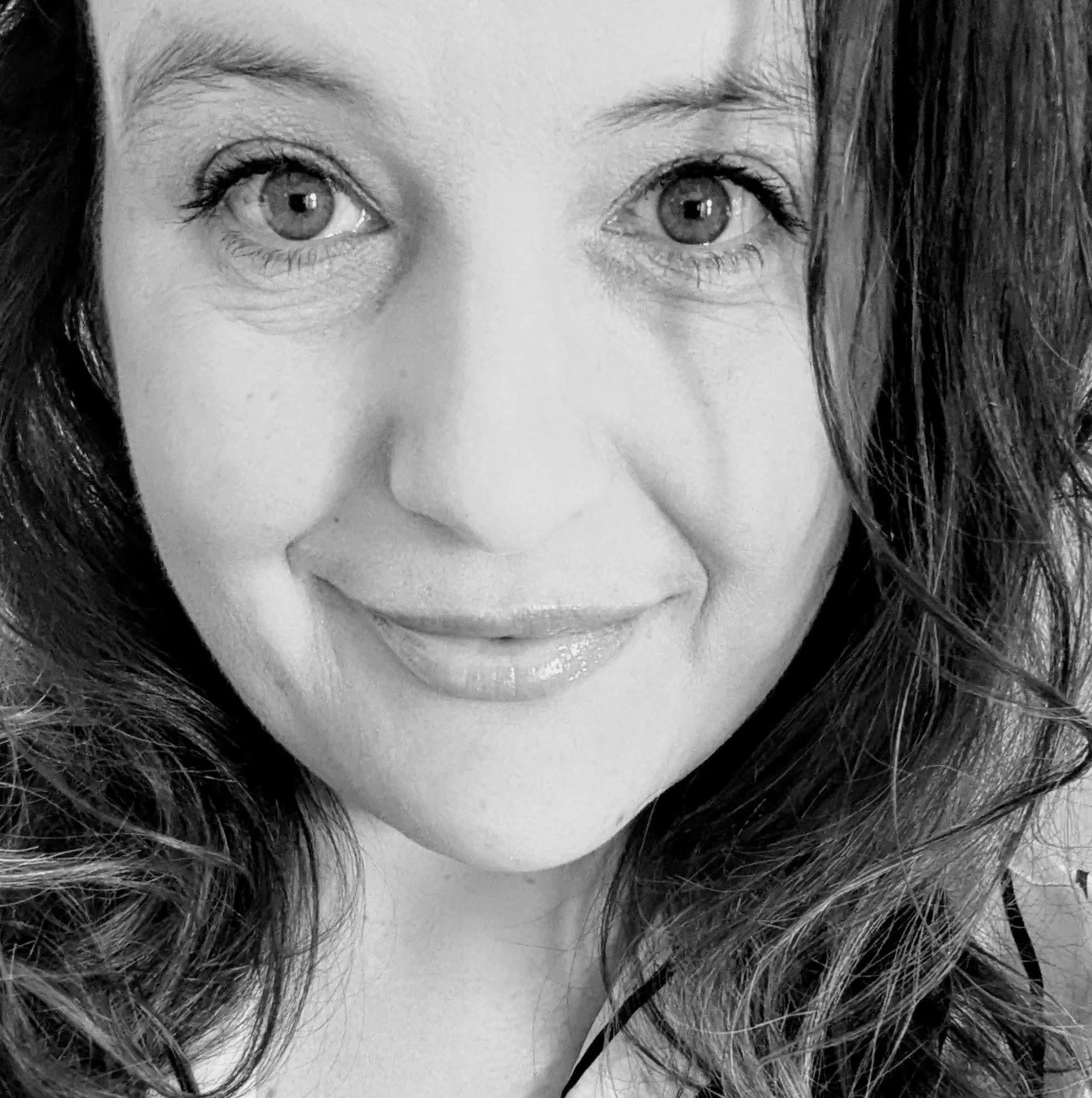 Close-up of a woman's face in black and white, focusing on her eyes and lips. She has dark hair and light skin.
