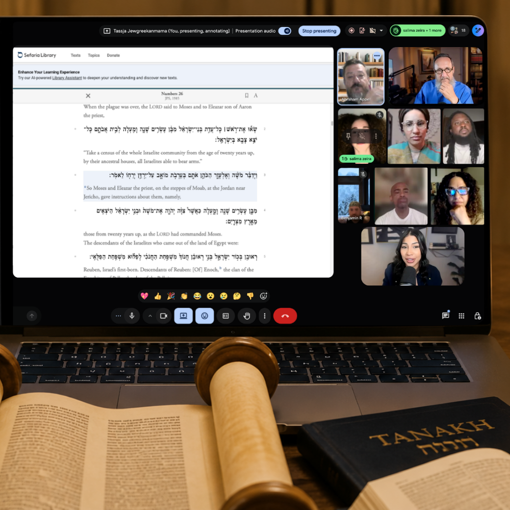 Laptop screen displaying a virtual Bible study group with multiple participants and a shared screen showing text from the Bible, including Hebrew and English translations. In front of the laptop, there are two open books, one with Hebrew text and the other titled 'Tanakh,' along with a wooden Torah scroll.