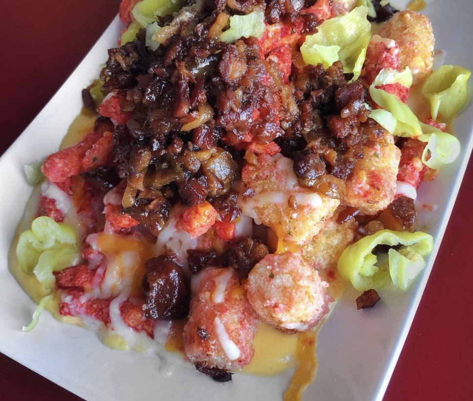 Close-up of a plate of loaded taco salad with seasoned ground beef, shredded cheese, lettuce, tomato, and crispy fried chicken bites.
