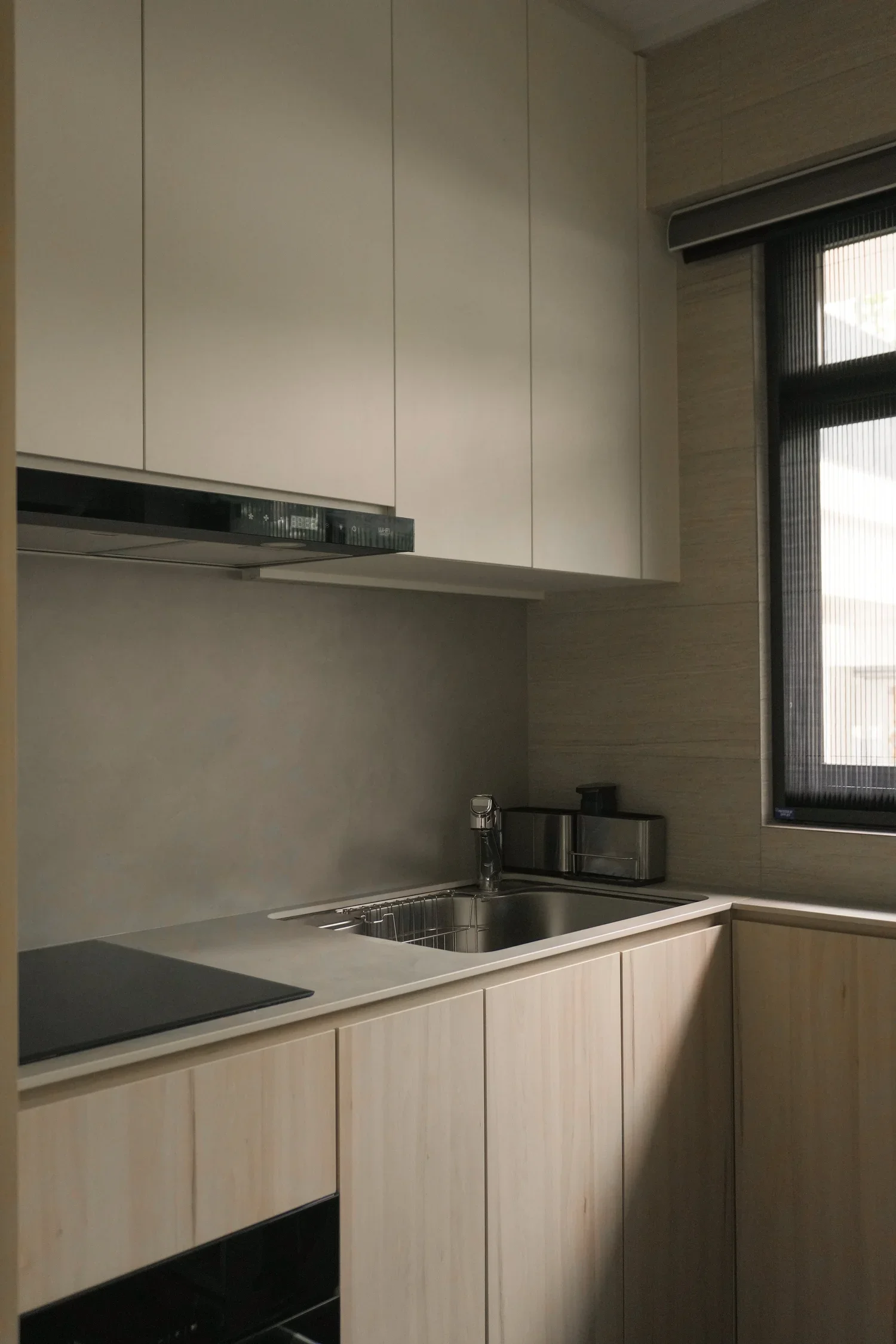Modern kitchen with beige cabinetry, a stainless steel sink, a window with blinds, and built-in appliances.