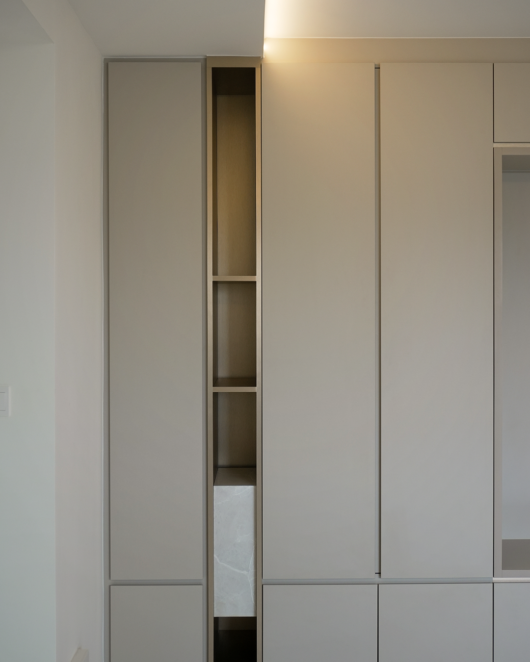 Modern built-in wardrobe with closed cabinetry and open shelves, in a neutral color scheme.